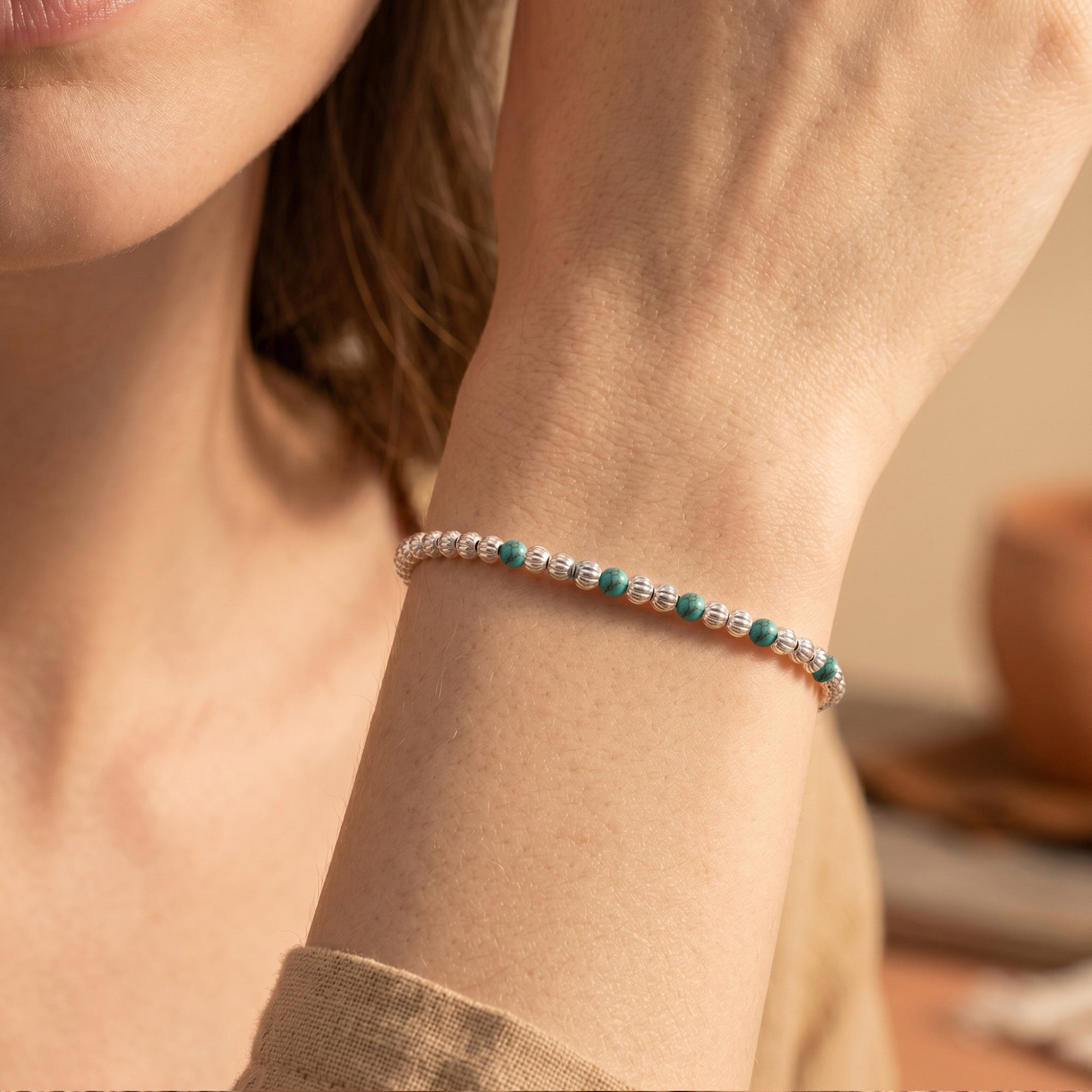 Close-up of silver and turquoise bead bracelet on a wrist.