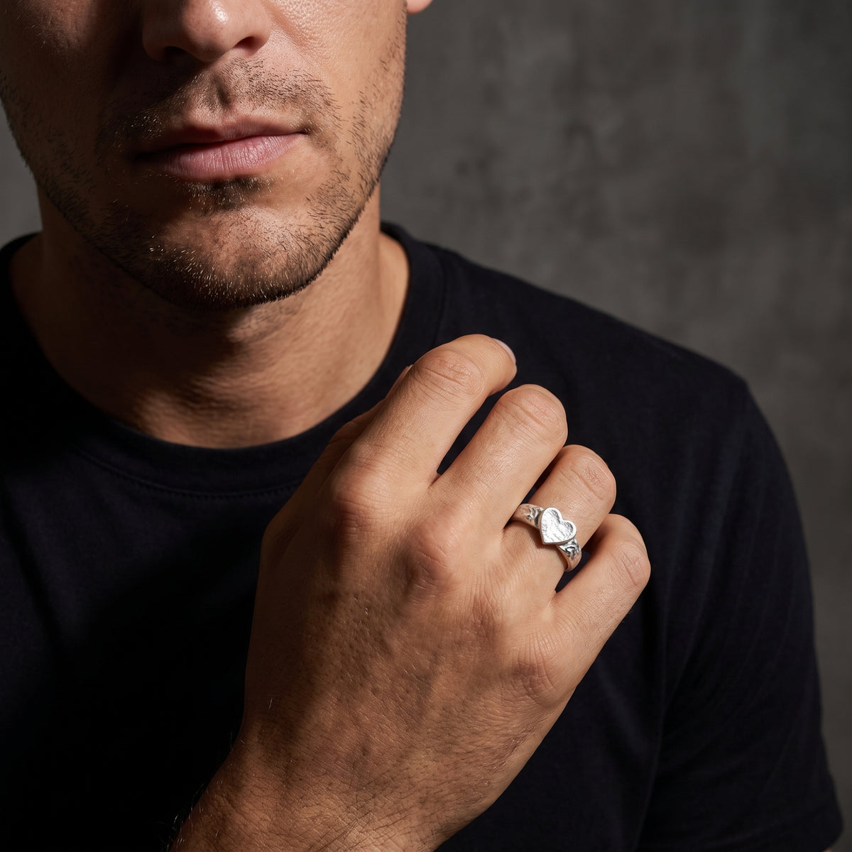Man wearing the hammered heart ring on his ring finger with his hand resting against his chest.