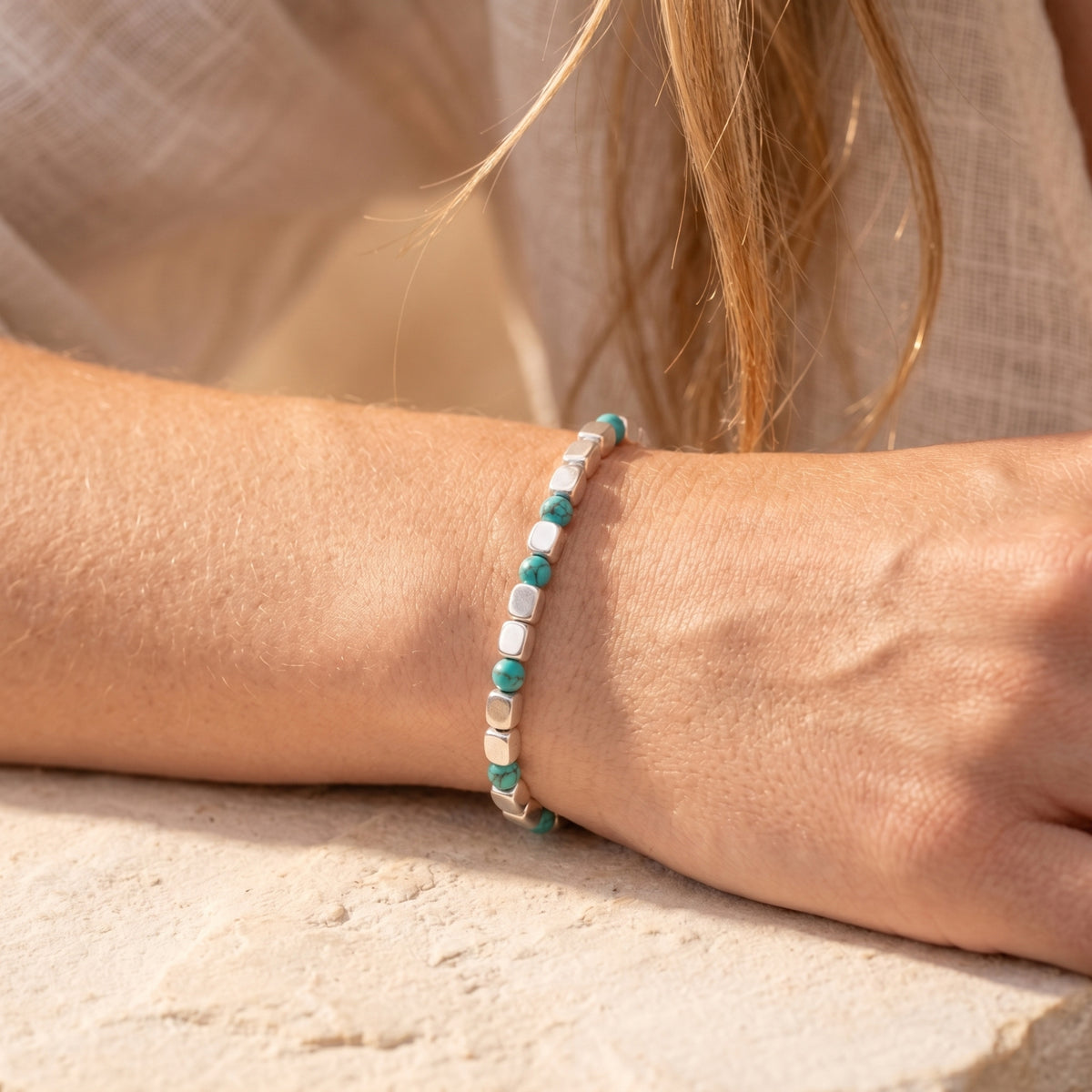 Close-up of a silver and turquoise bead bracelet on a model's wrist.