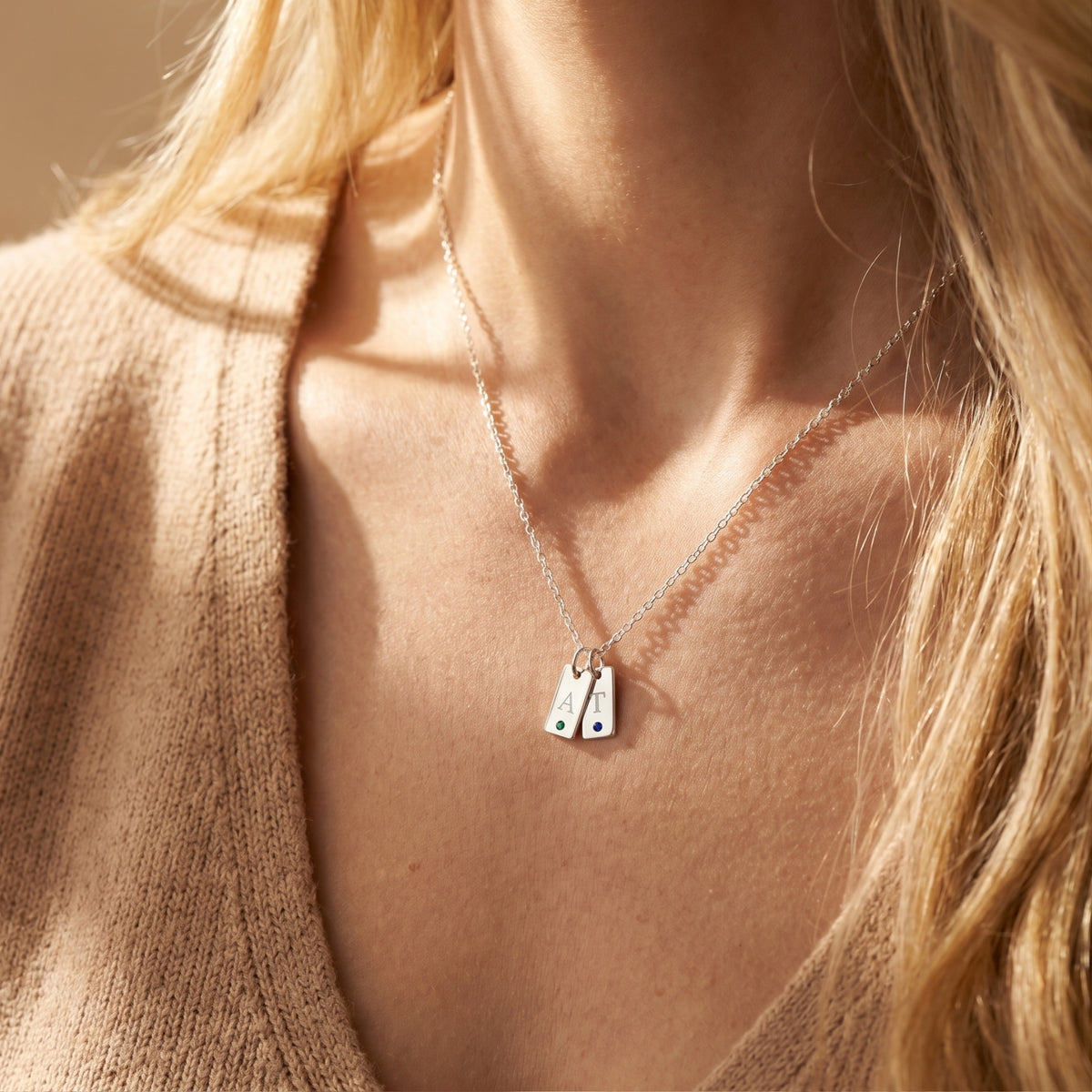 Silver Cecelia pendant necklace with two custom engraved initial tags and birthstones worn by a model.