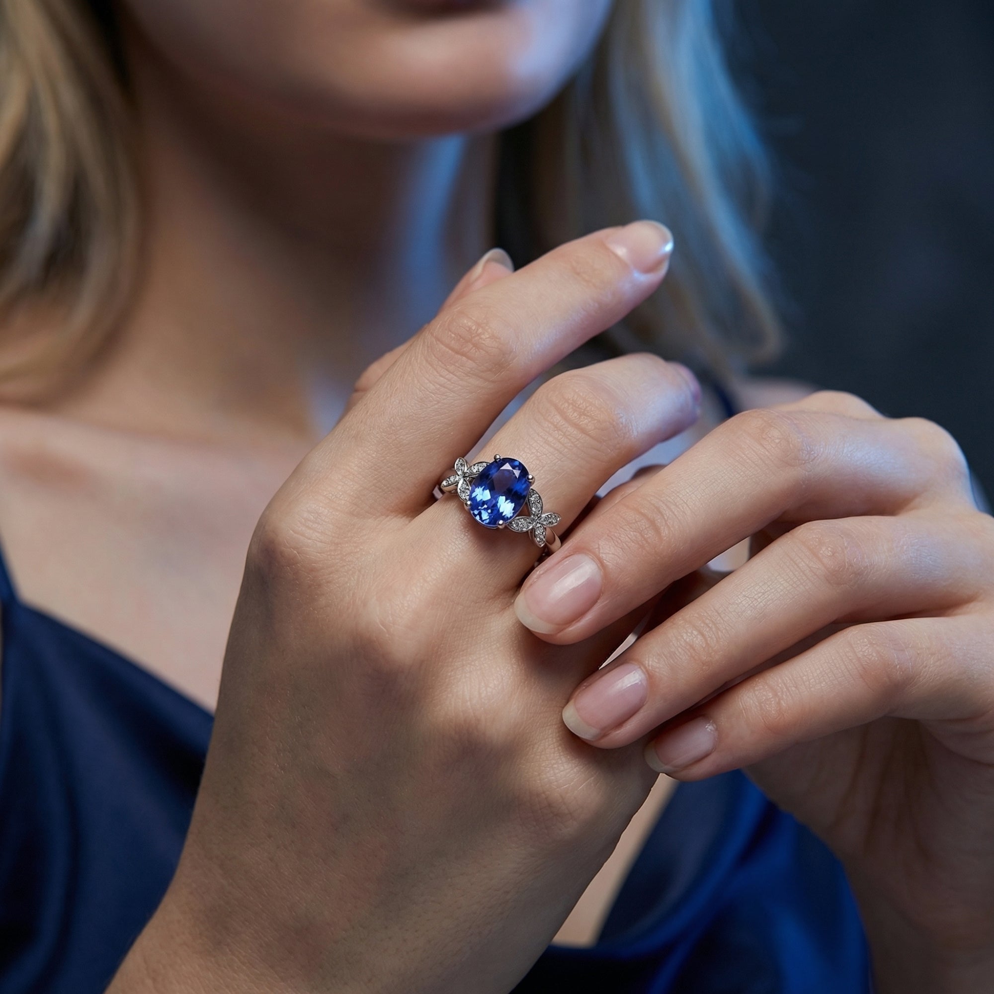 Woman wearing the oval tanzanite butterfly ring in 18K white gold, showcasing its size and color on the hand.