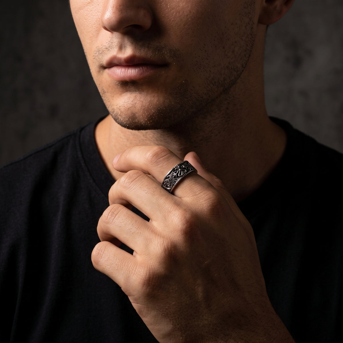 Close-up of a man wearing the oxidized silver filigree ring on his index finger near his neck.