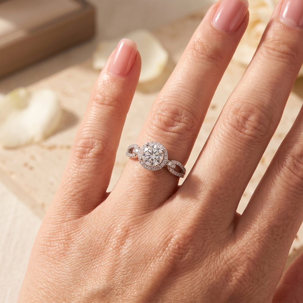 Overhead view of the halo ring with a pavé infinity twist band worn on a finger.