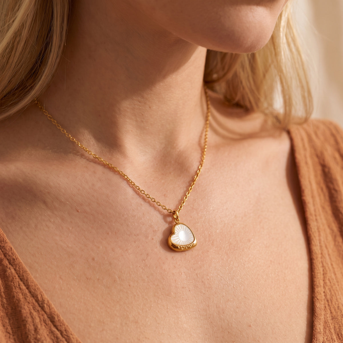 Chest-level model view showcasing the gold-tone heart pendant resting near the collarbone.