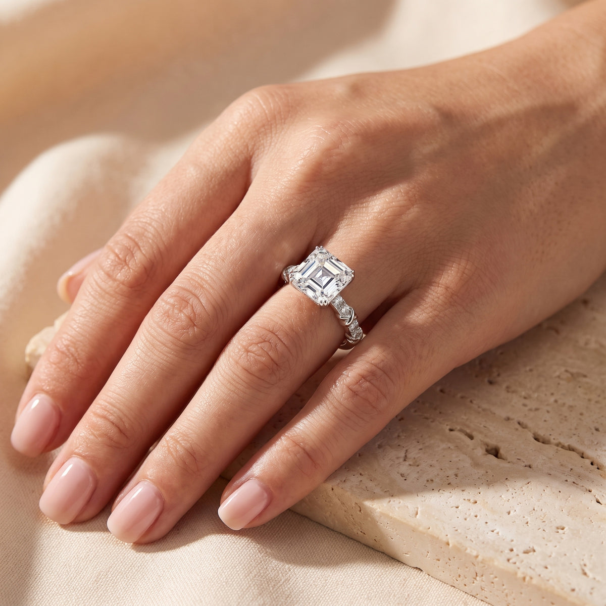 Top-down view of the silver ring worn on a hand, showing its clear emerald-cut center stone and twisted accent band.