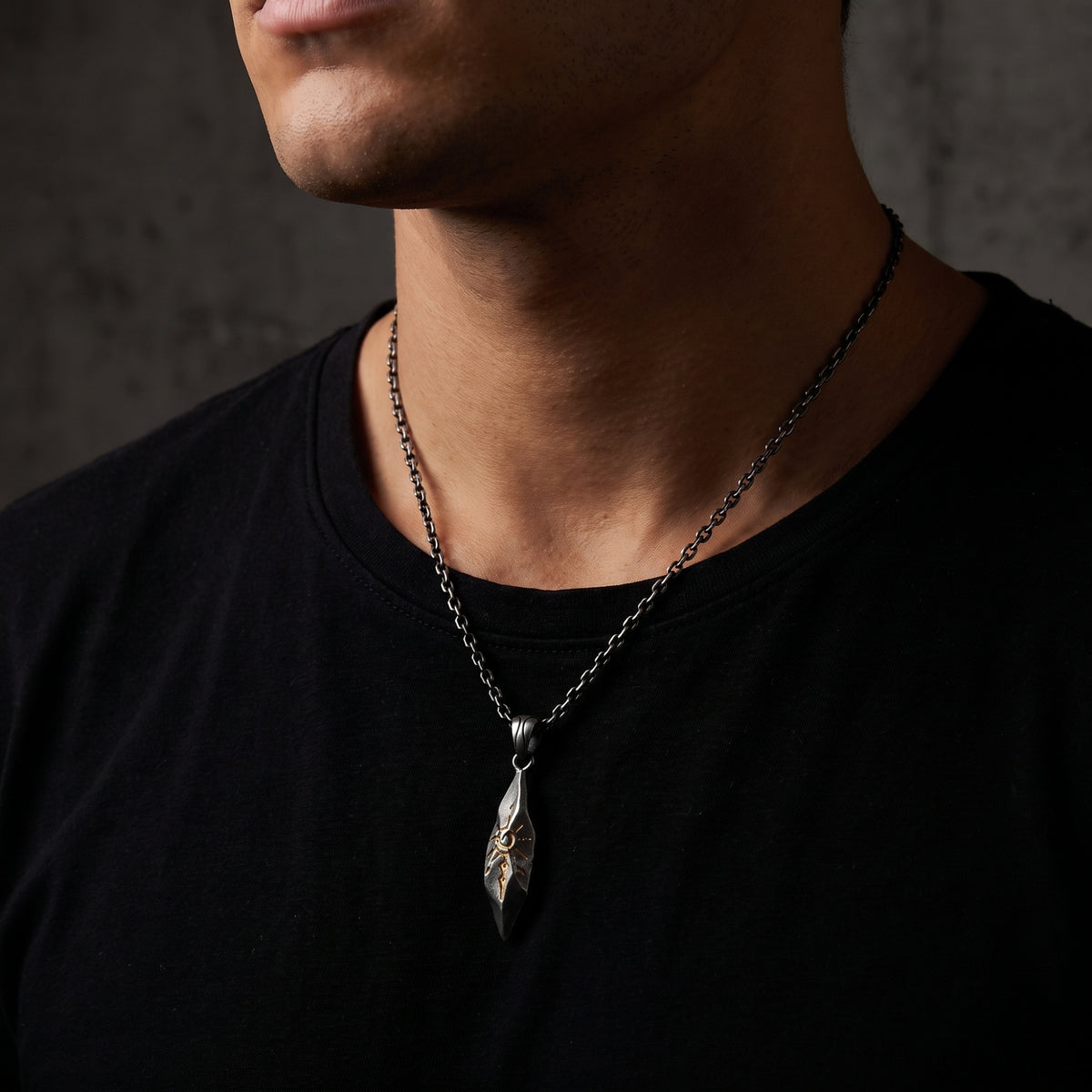 Close-up of a model wearing the textured silver sunburst pendant on a black T-shirt