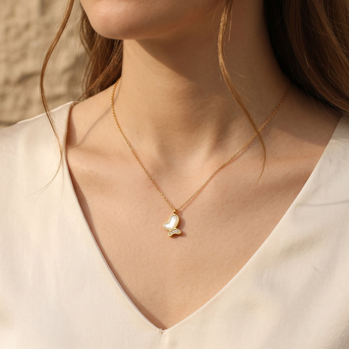 Front view of the gold Brielle butterfly necklace with mother of pearl inlay worn by a model.