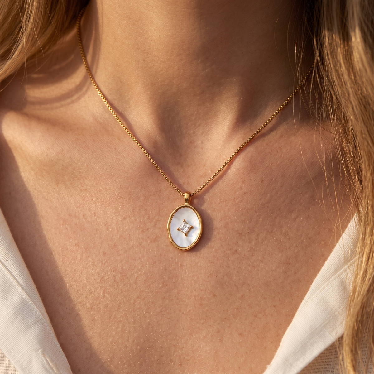 Close-up of the 18K gold Lucelle necklace with mother of pearl and princess-cut diamond pendant worn by a model.
