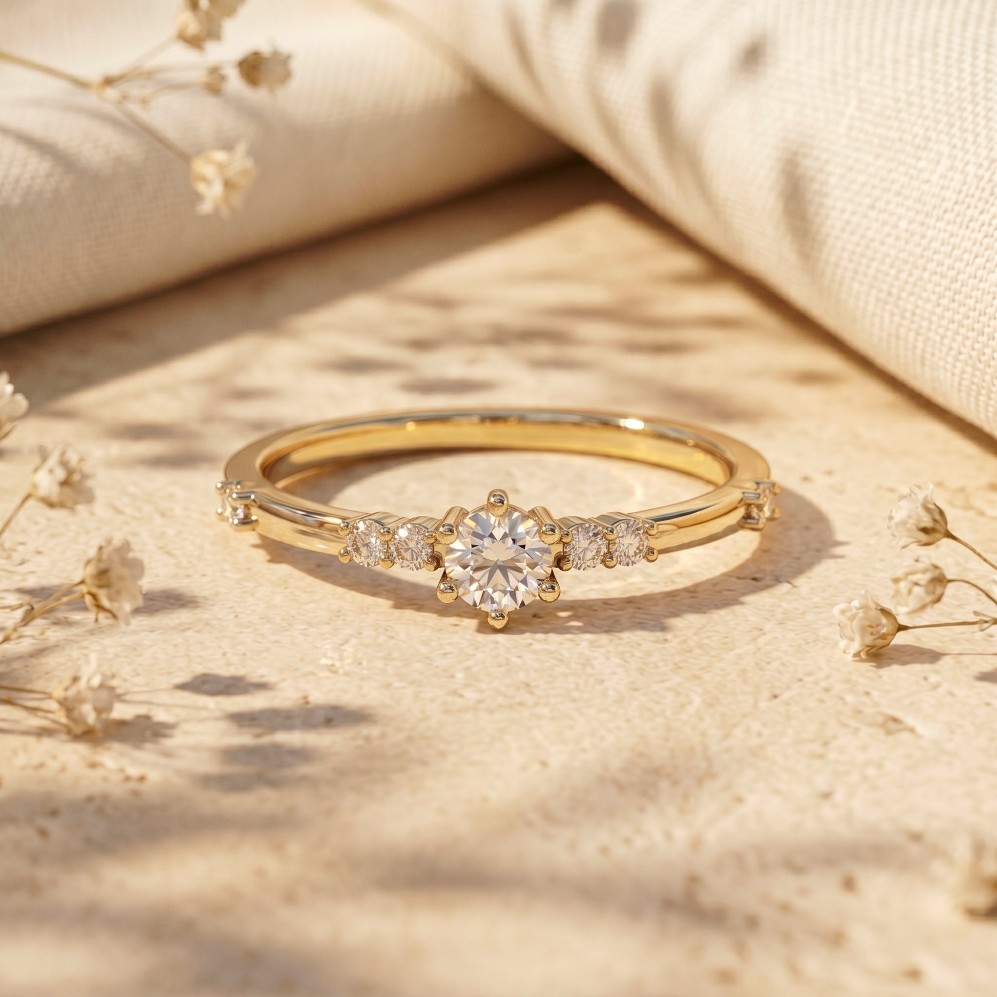 Gold plated round cut moissanite promise ring on a textured stone surface with soft shadows and floral accents.