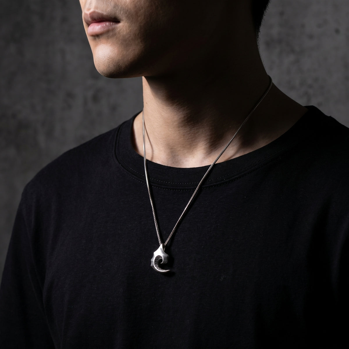 Model wearing the silver tidal scroll pendant necklace, displayed from chest to jawline.