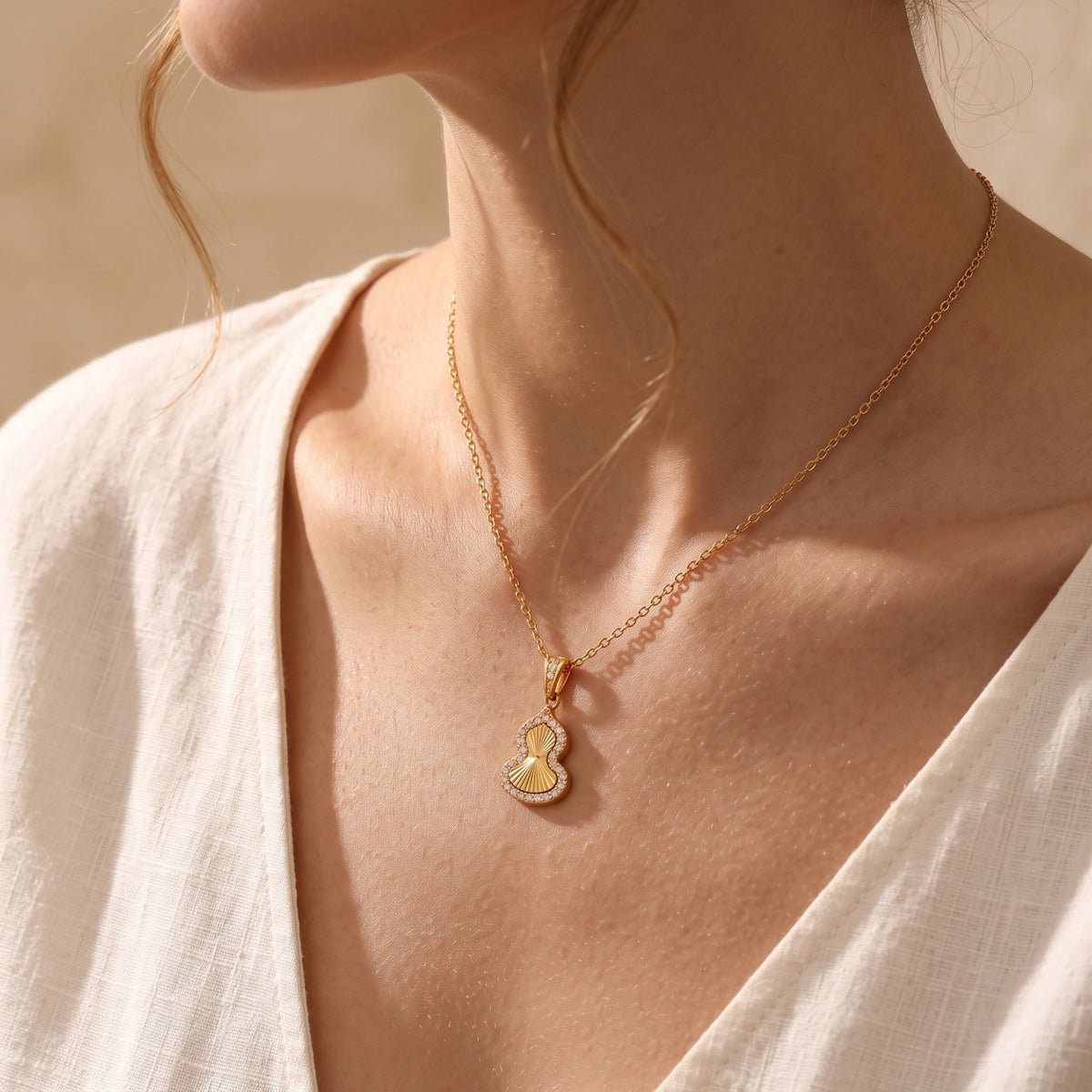 Model wearing the gold Sorsha pendant necklace featuring a radial textured gourd design.