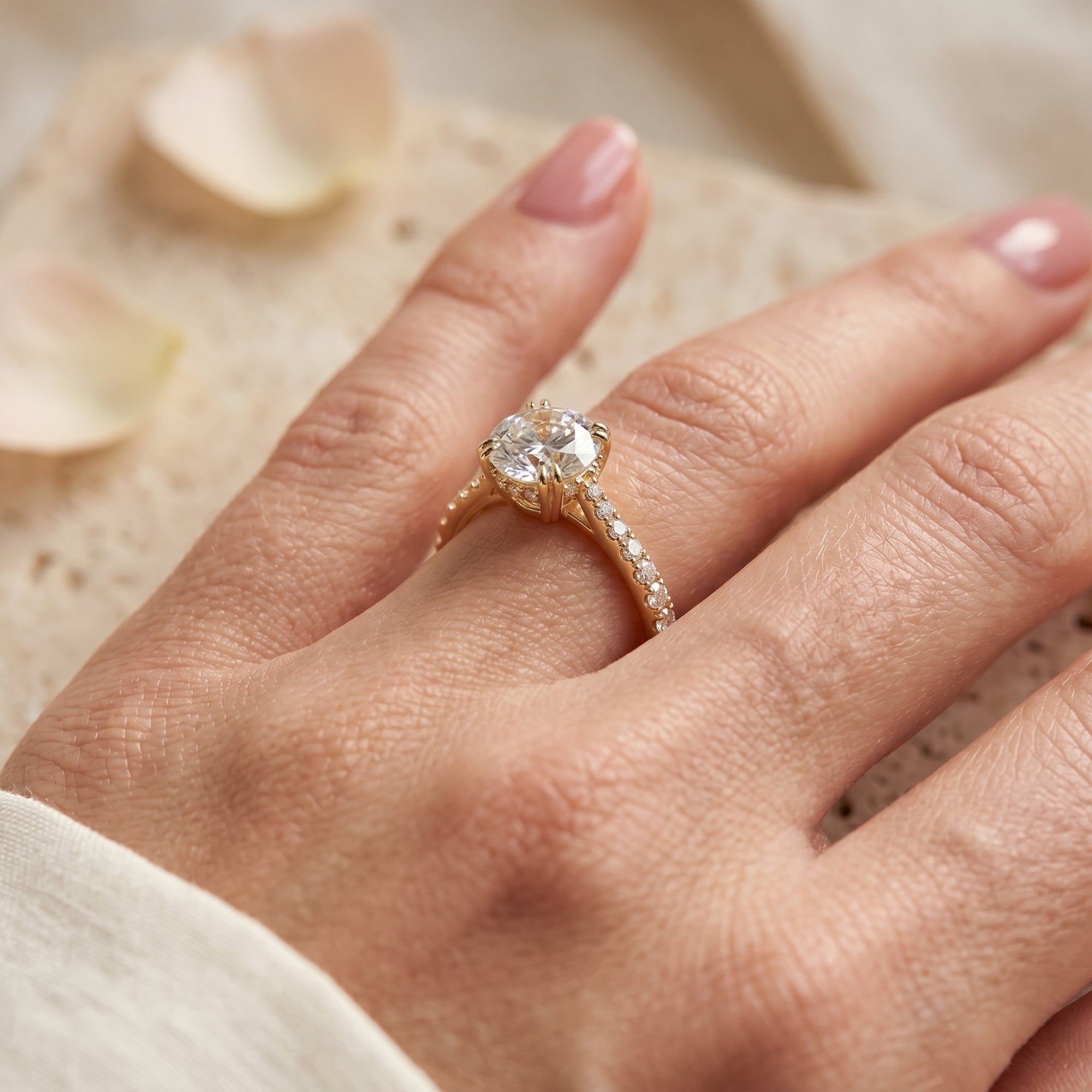 Close-up side profile of a gold round moissanite ring with a hidden halo and pavé band on a finger.