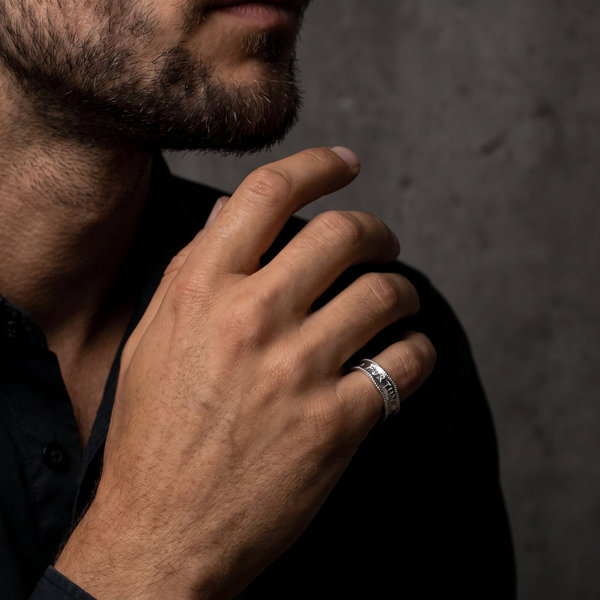 Model wearing the silver Fortuna engraved ring on his ring finger with hand posed near his chin.
