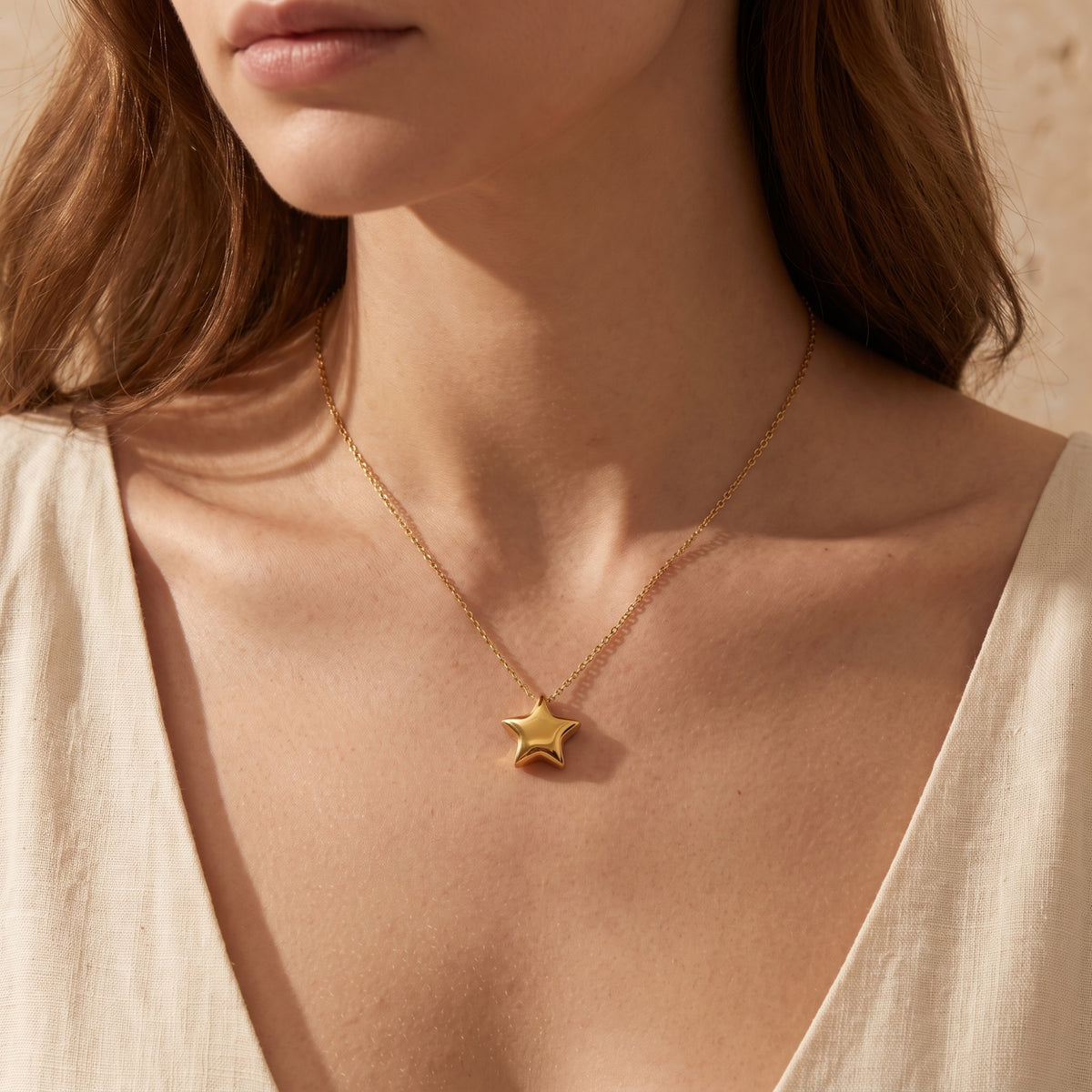 Front view of a model wearing the gold-tone puffed star pendant necklace centered on her neckline.