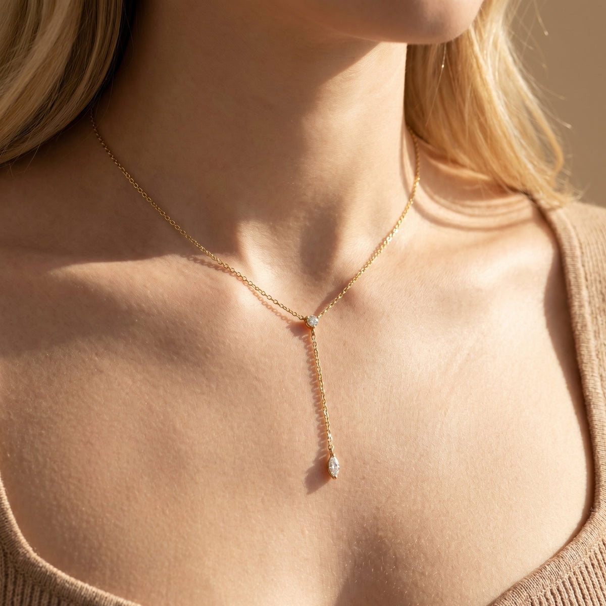 Model wearing the gold Rosamel lariat necklace with round and marquise-cut moissanite stones.