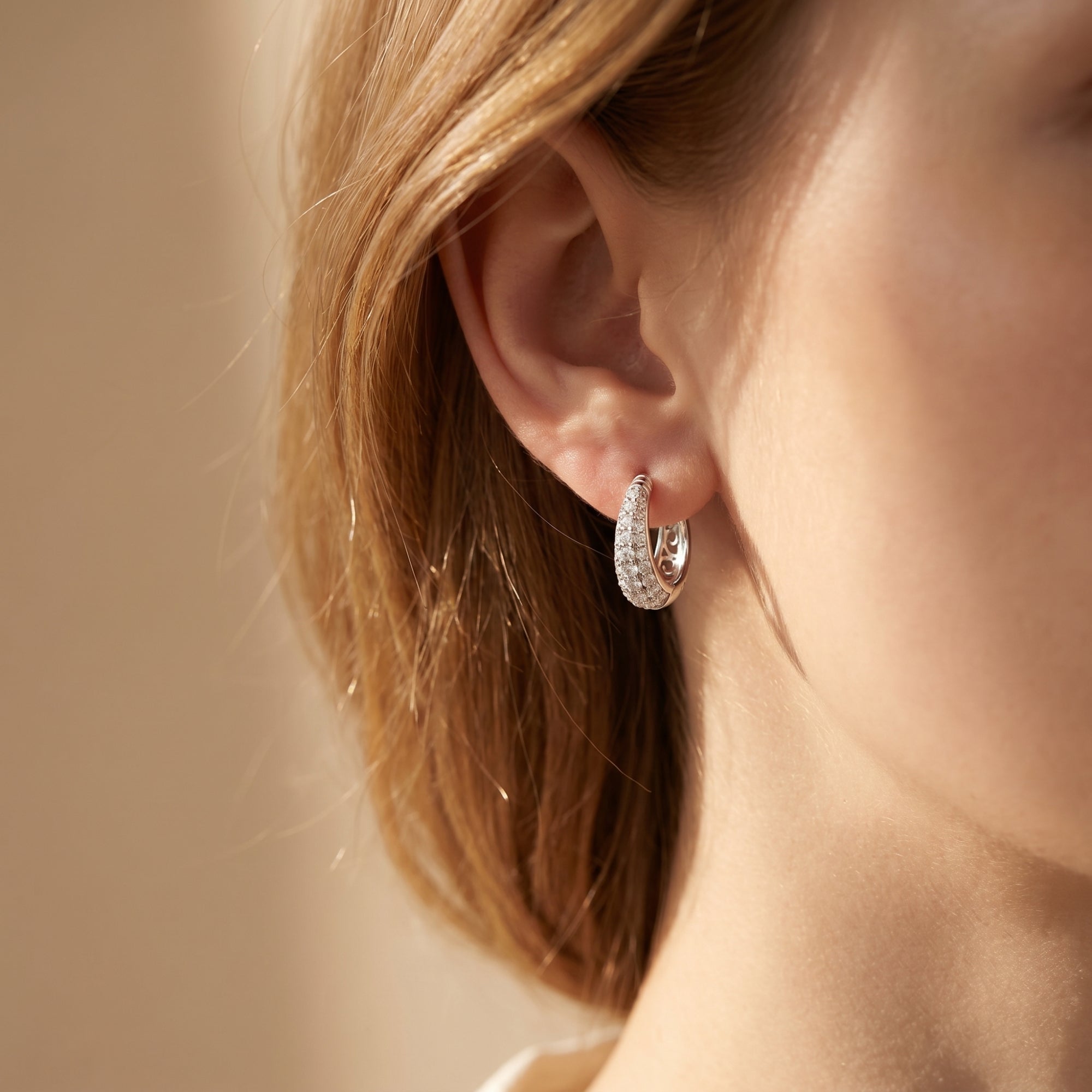 Moissanite hoop earrings with brilliant round stones worn on a woman's ear.