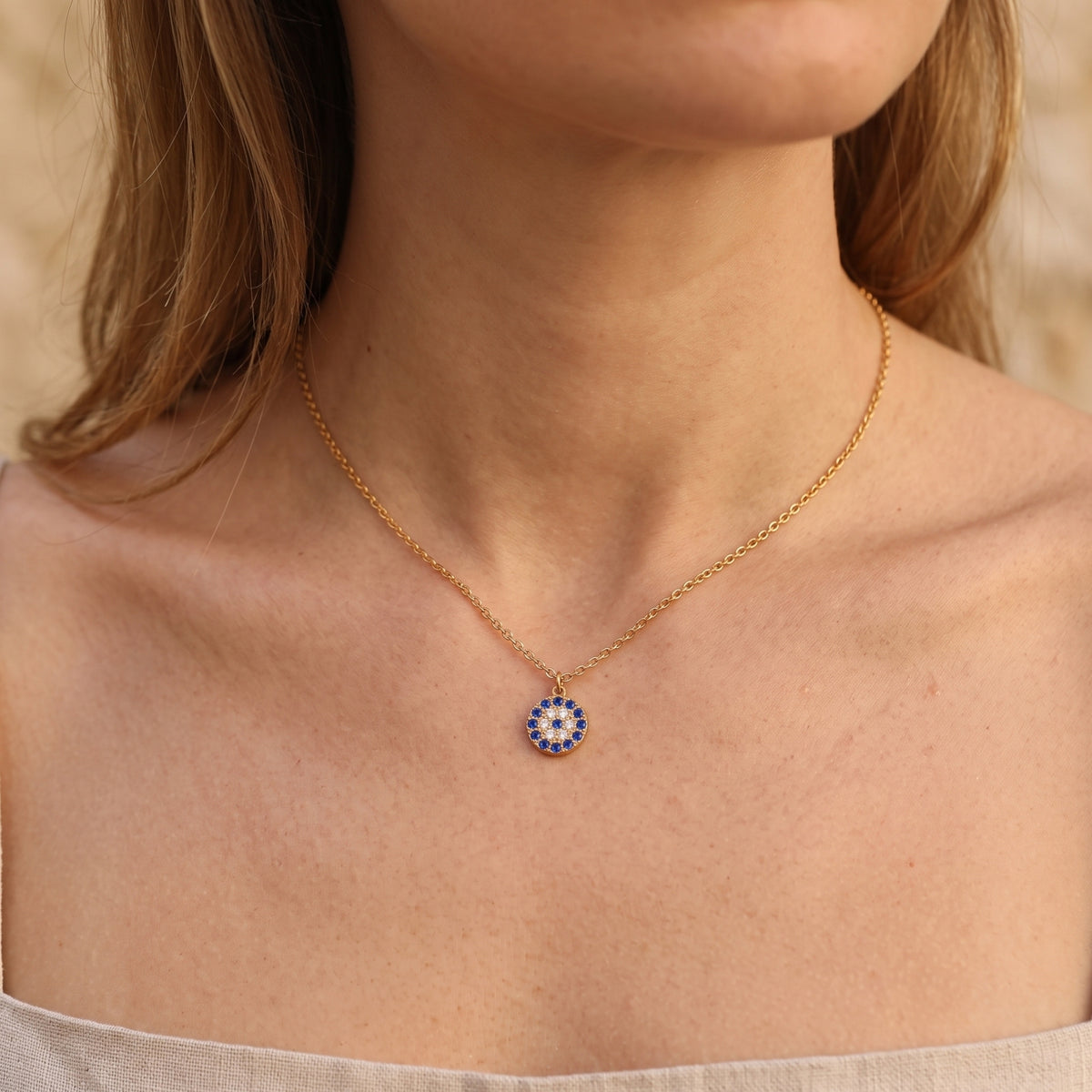 Model wearing the 18K gold PVD Stellis pendant necklace with blue and white pave stones.