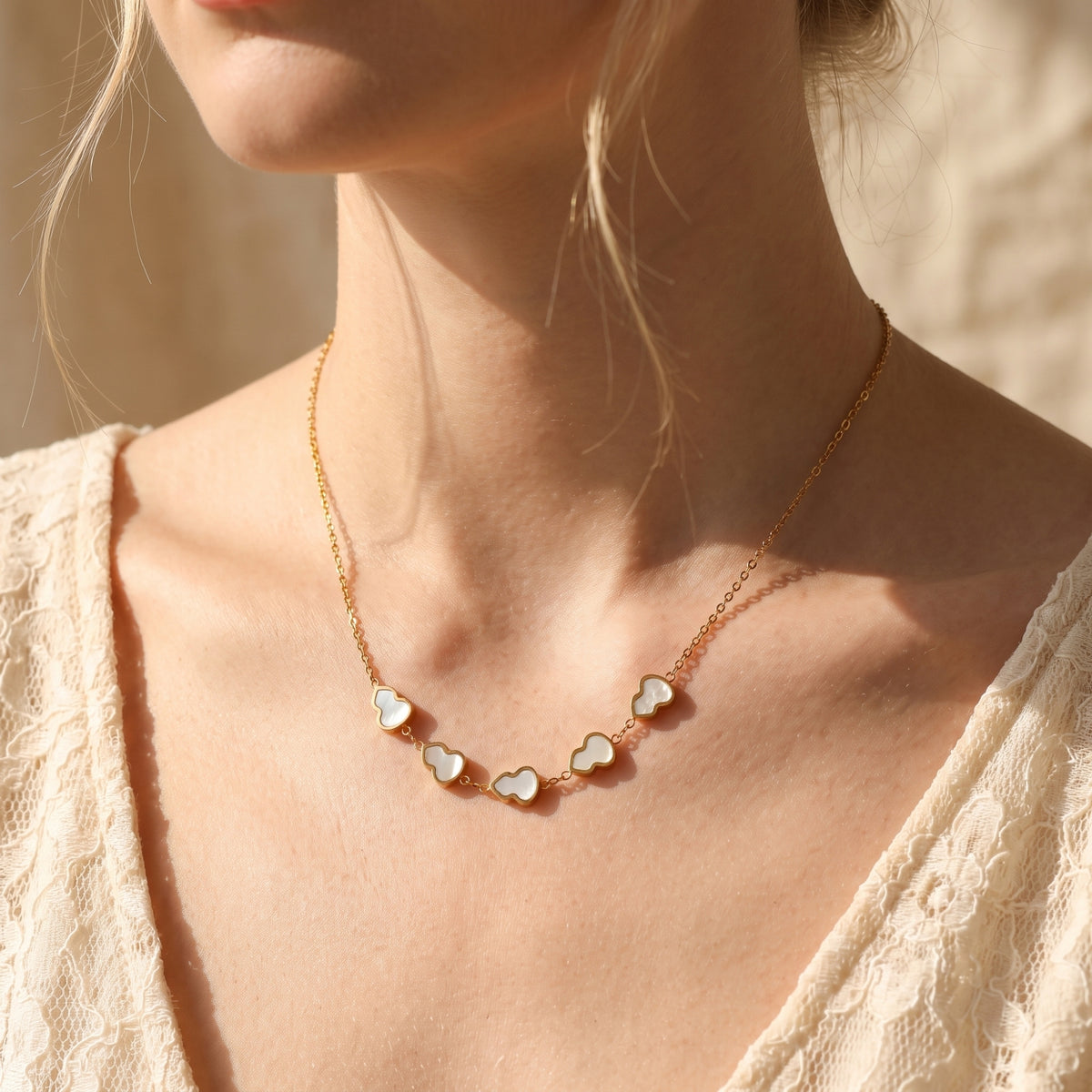 Model wearing a gold mother-of-pearl gourd station necklace with a white lace top.