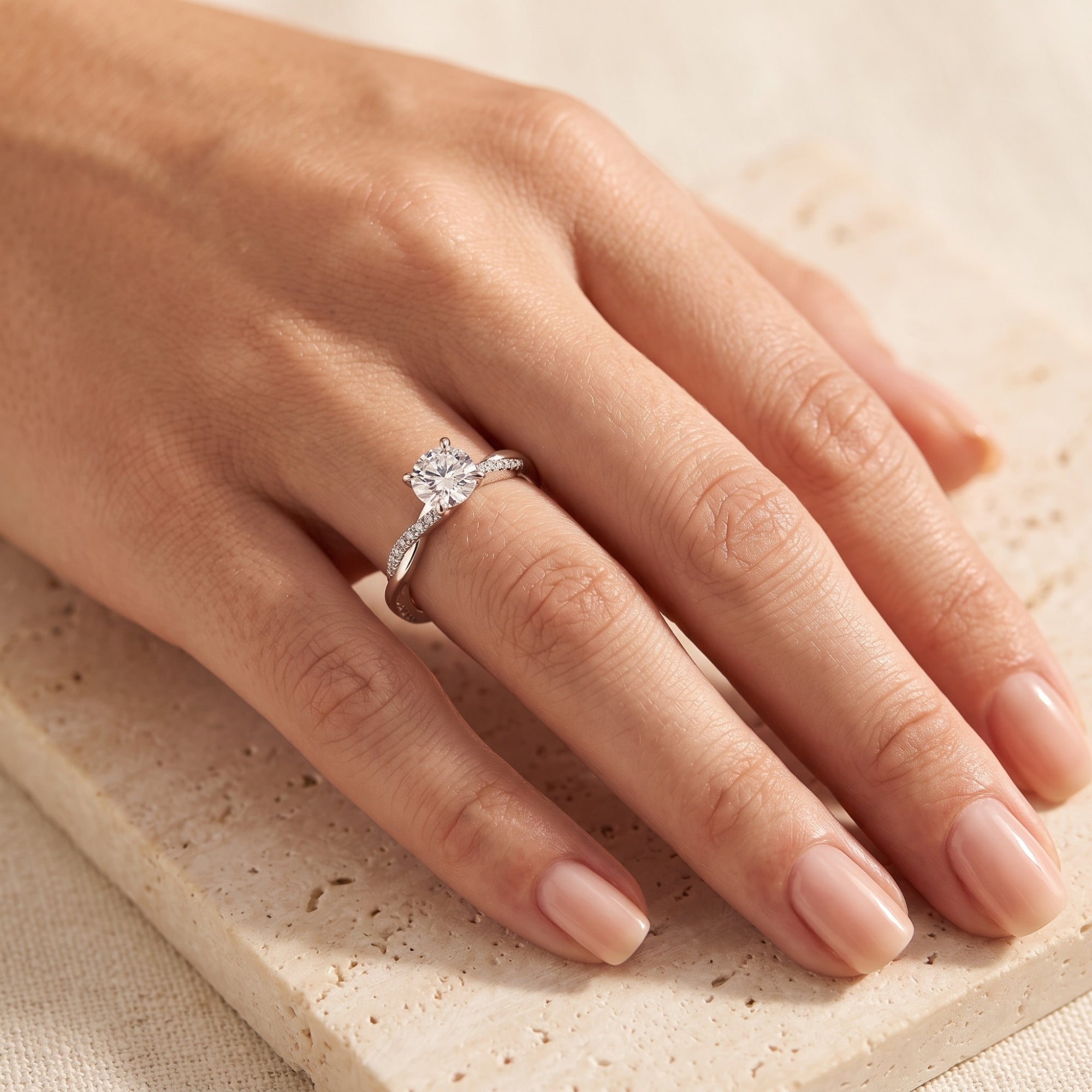 Sterling silver round-cut simulated diamond solitaire ring with a twisted band shown on a woman's finger.
