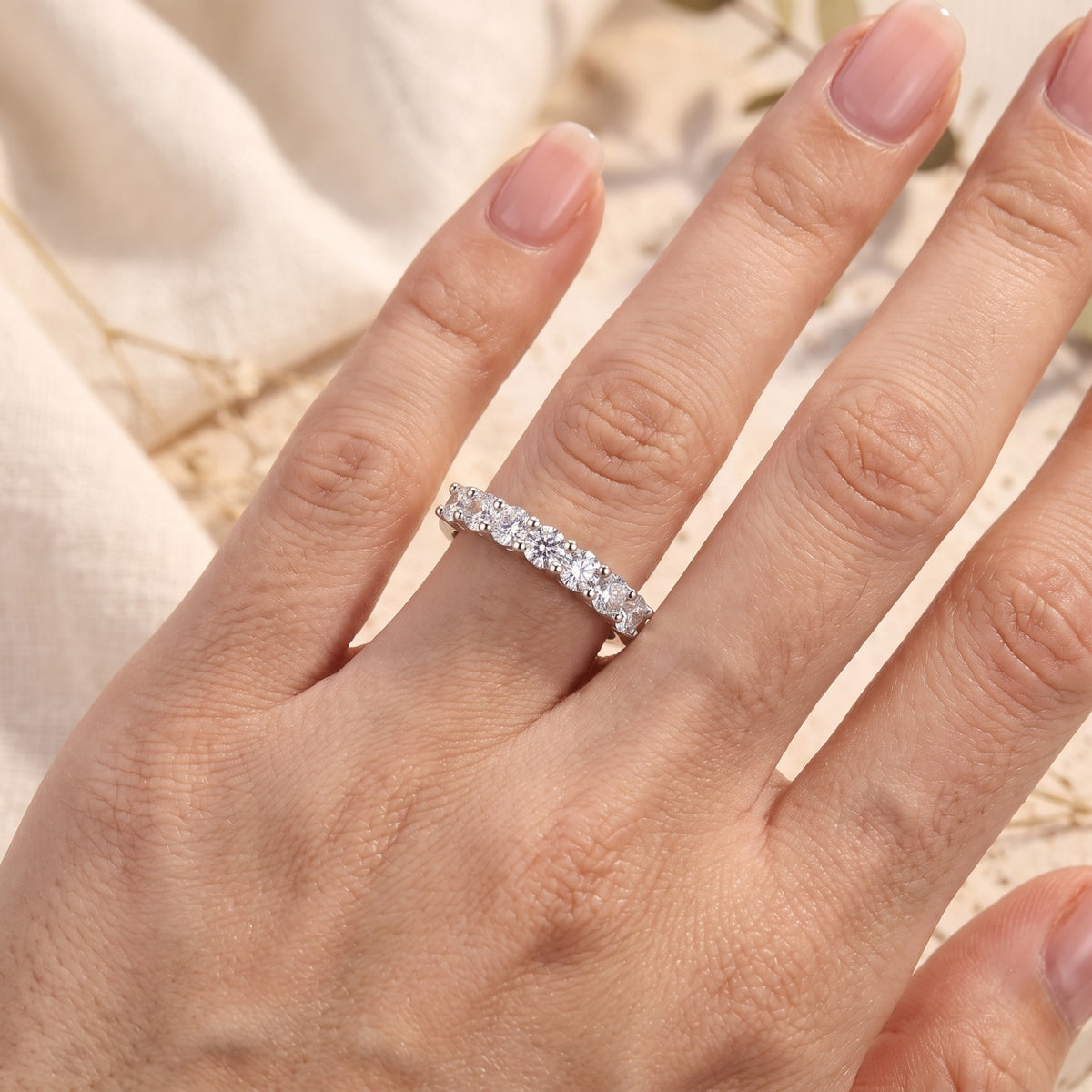 Close-up top view of the silver seven-stone band ring worn on a hand.