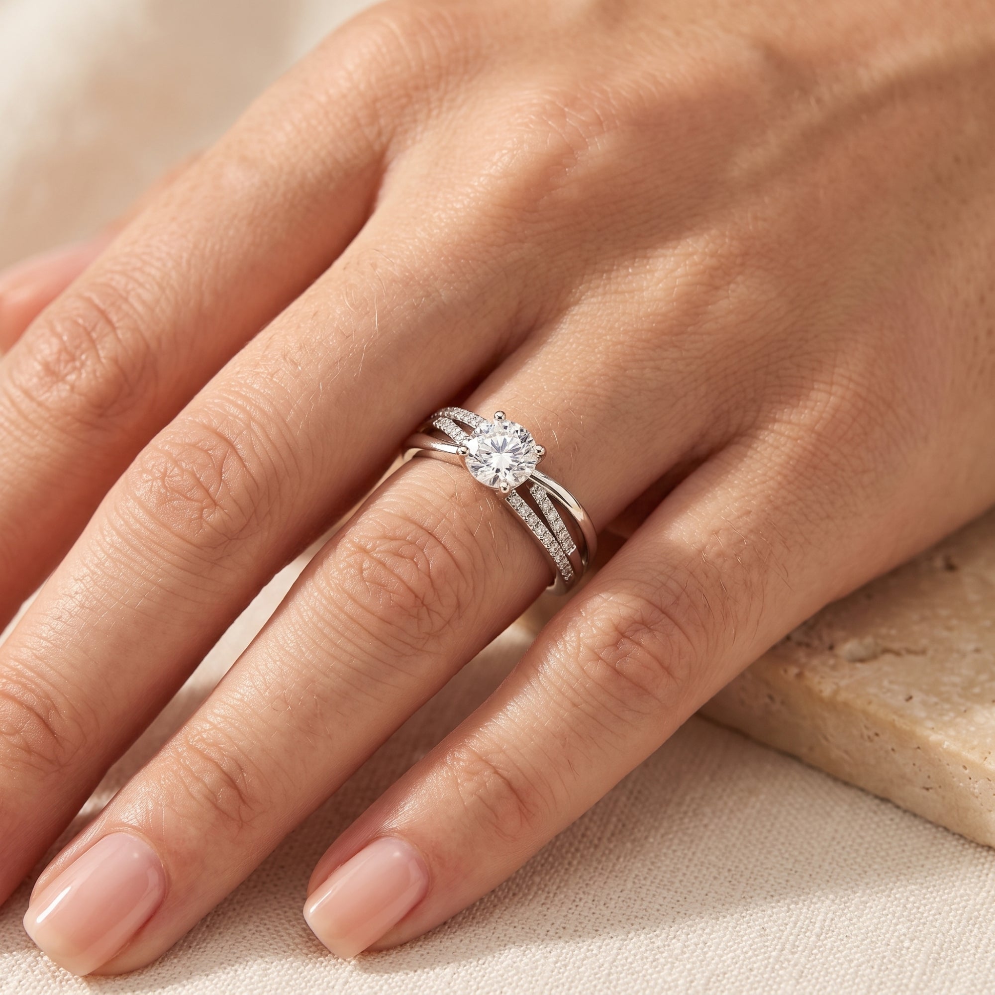 Top-down view of the sterling silver triple-band crossover ring with a round simulated diamond on a model's hand.