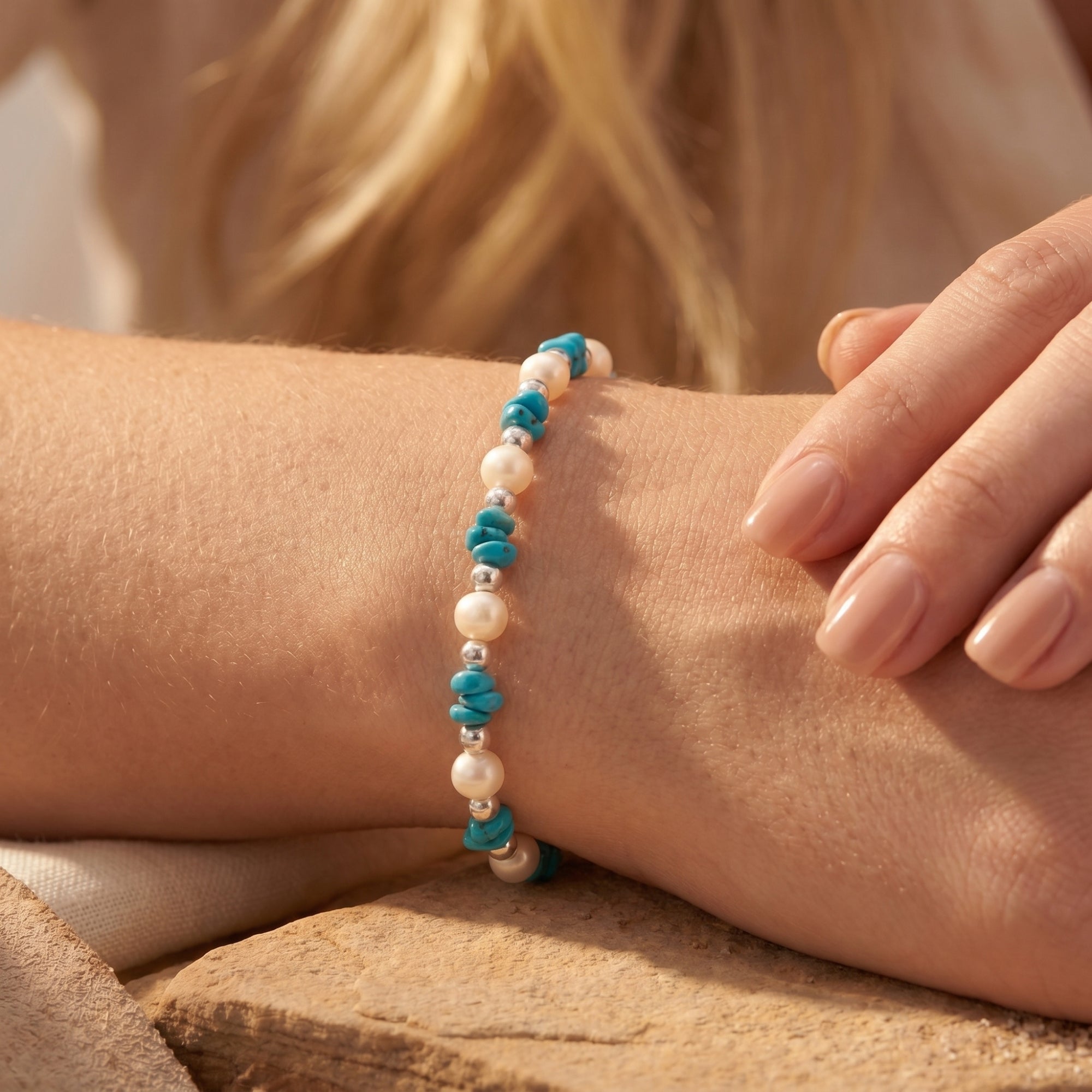 Close-up of turquoise and pearl silver beads on a wrist.