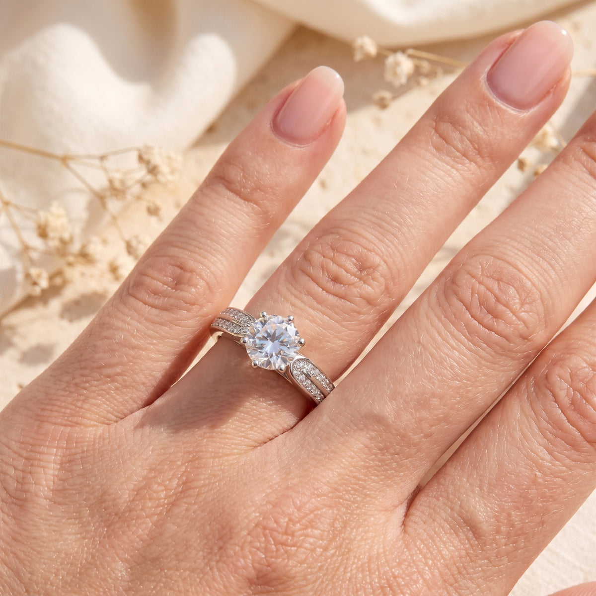 Top-down view of a hand wearing a silver split-shank ring with a sparkling round center stone.