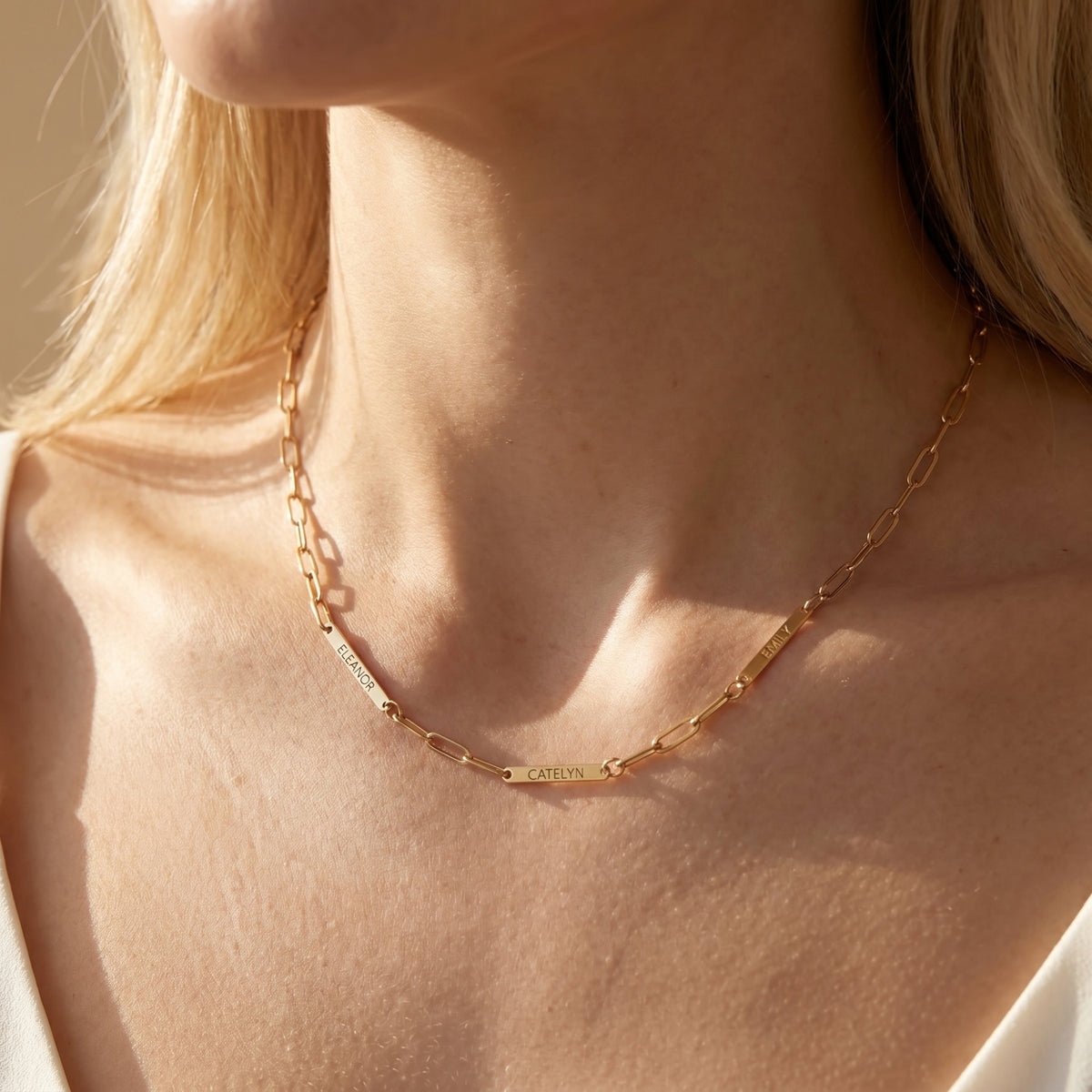 Gold stainless steel custom name paperclip necklace on model's neck.
