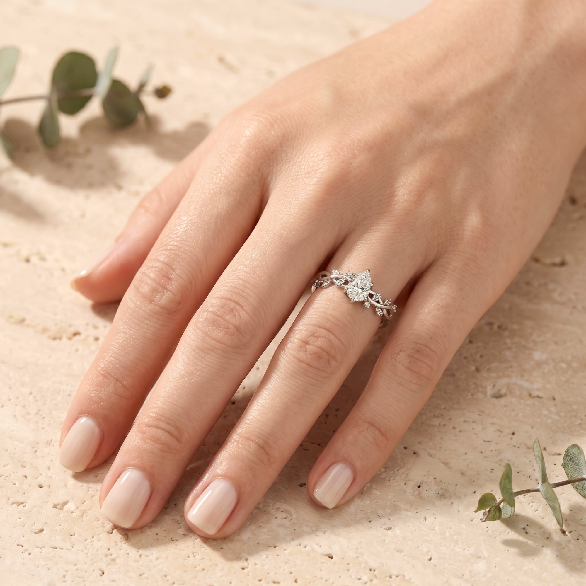 Pear cut moissanite silver ring on a model's finger, showing scale and vine design.