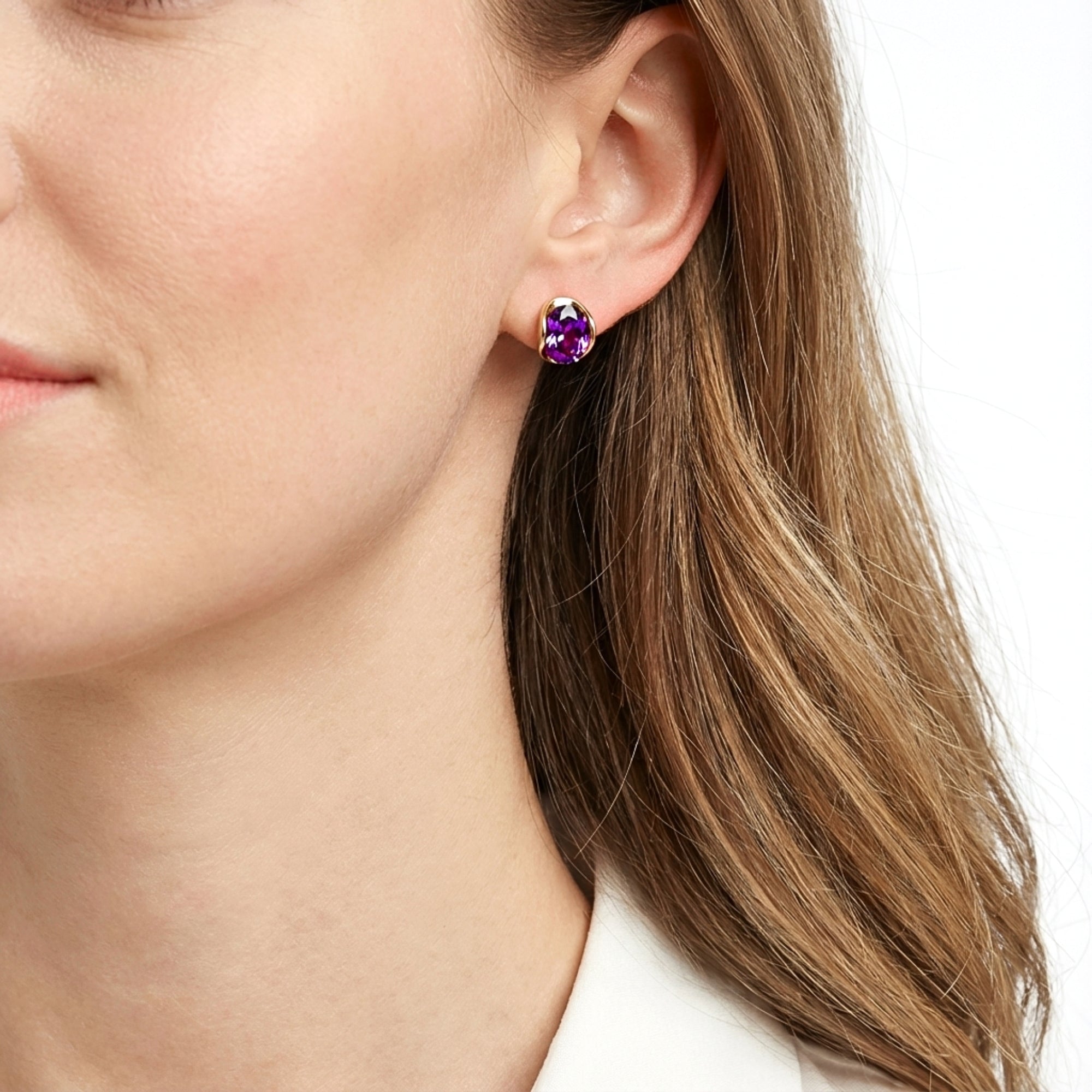 Model wearing the Hera 18K gold vermeil hoop earrings featuring oval cut purple simulated amethyst stones.