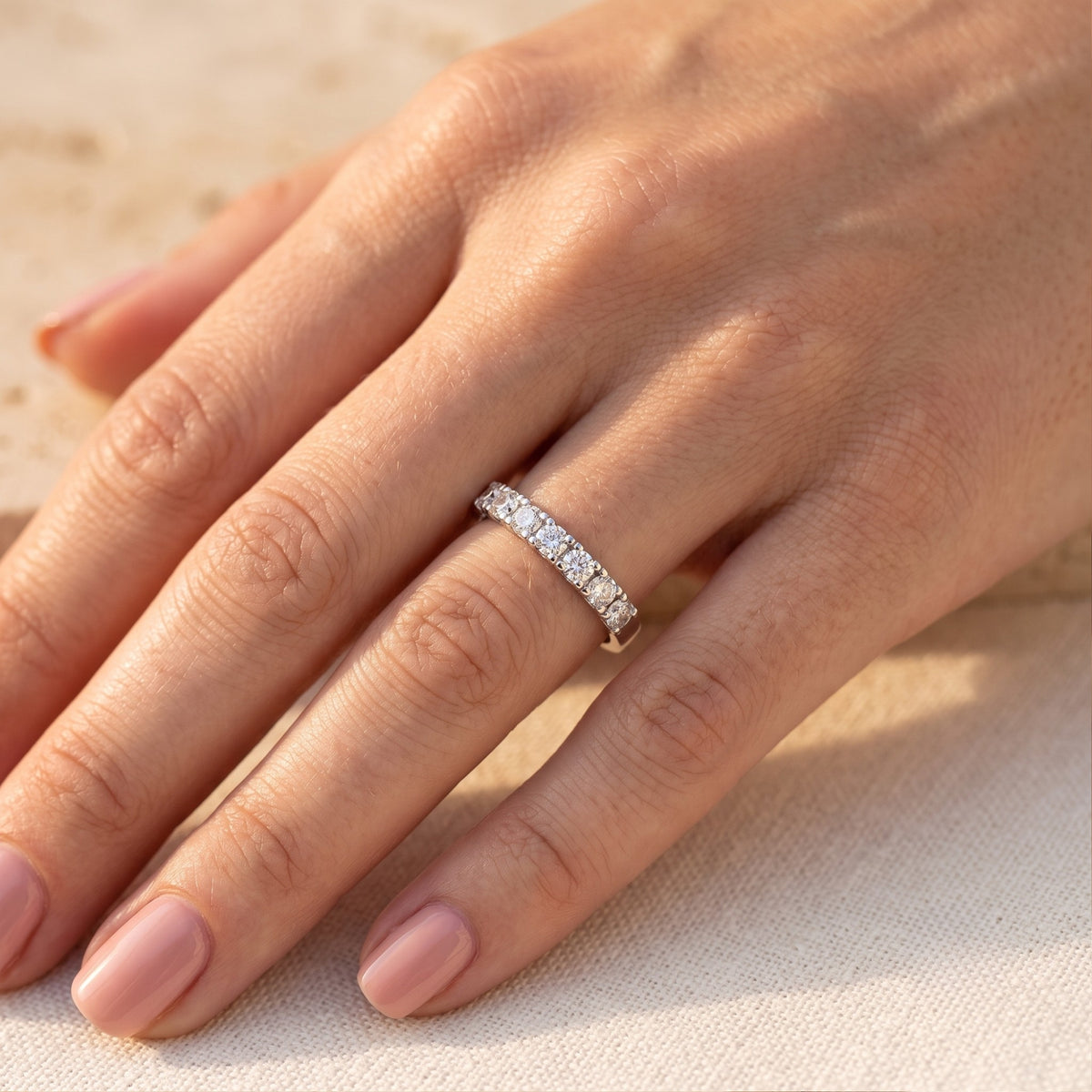 The Evadienne silver eternity promise ring with round-cut simulated diamonds worn on a hand with a neutral background.