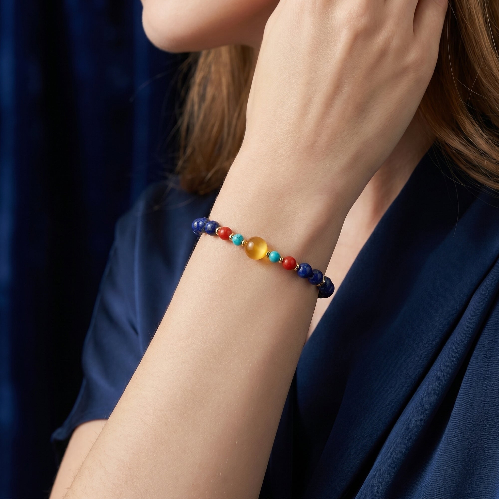 Side view of the Azure Glow 6mm lapis lazuli bracelet with gold-plated beads worn on a woman's wrist.
