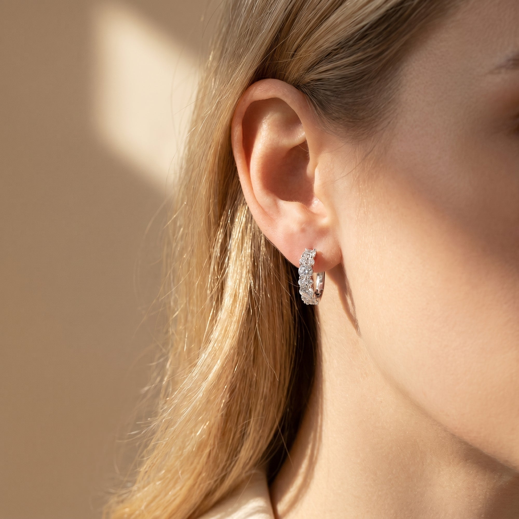 Silver moissanite hoop earring with round stones shown on a model.