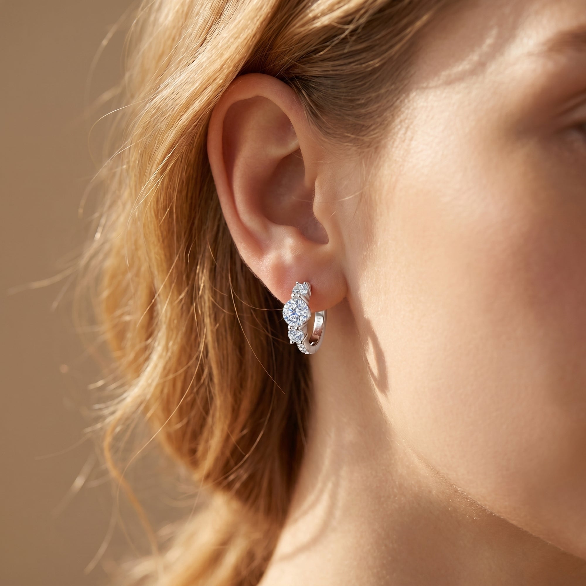 Woman wearing a silver moissanite hoop earring with round-cut stones.