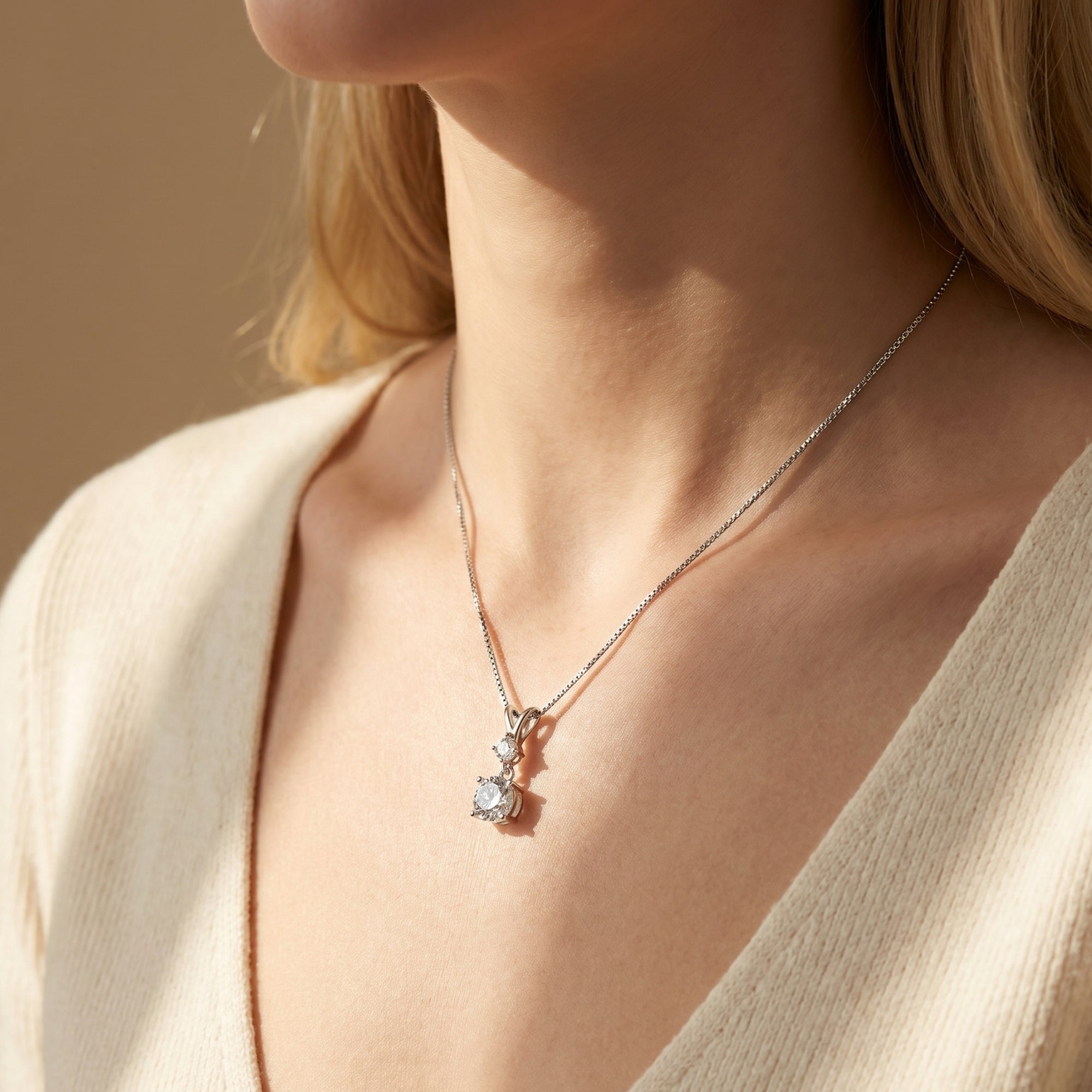 Silver moissanite pendant necklace displayed on a model wearing a cream V-neck top.