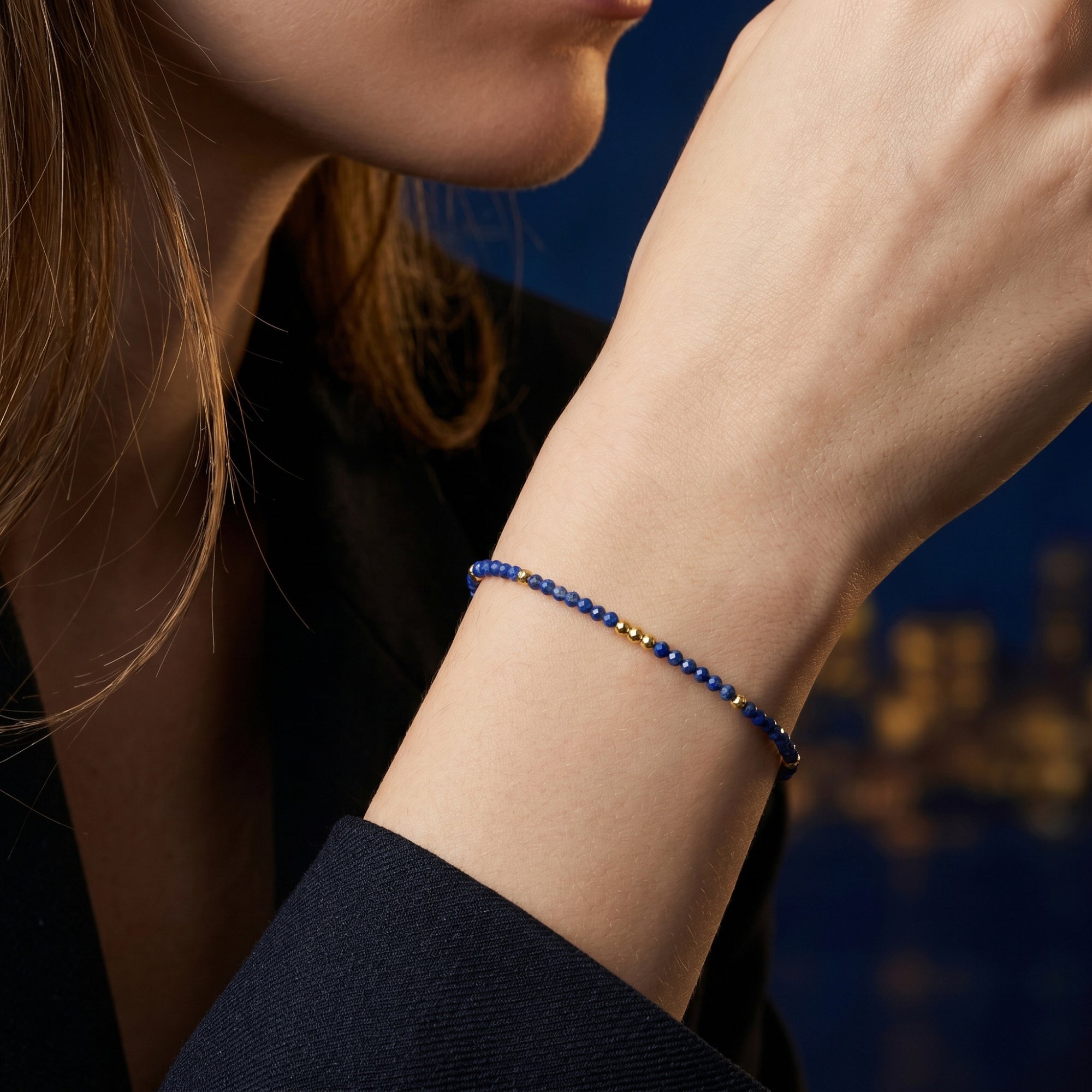 Close-up of a delicate lapis lazuli and gold bead bracelet styled on a model's wrist.