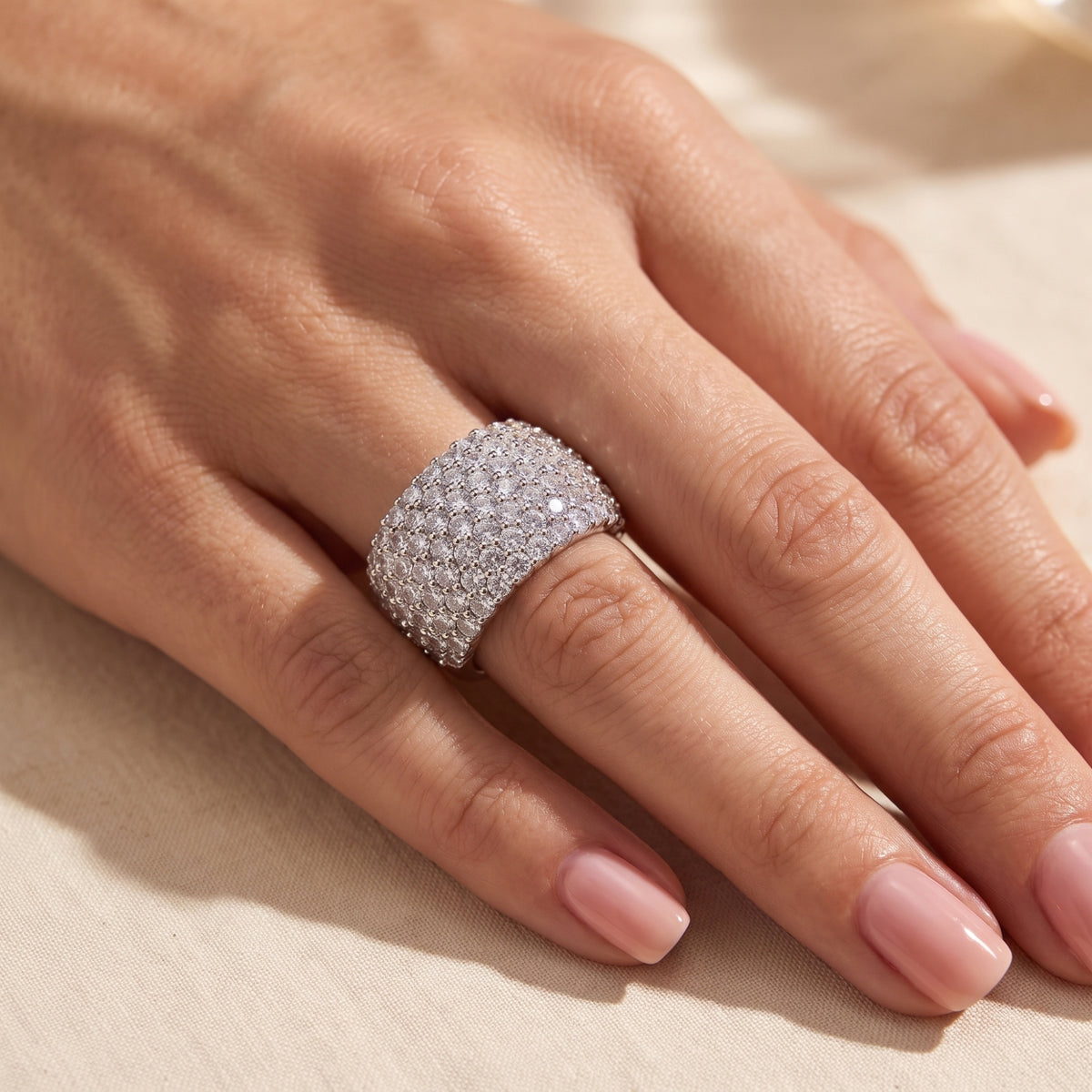 Angled view of a hand wearing the wide silver cobblestone pave ring.