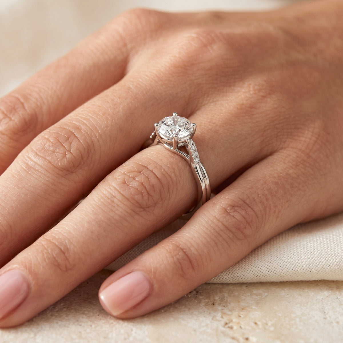 Angled view of round moissanite promise ring in silver worn on a hand.