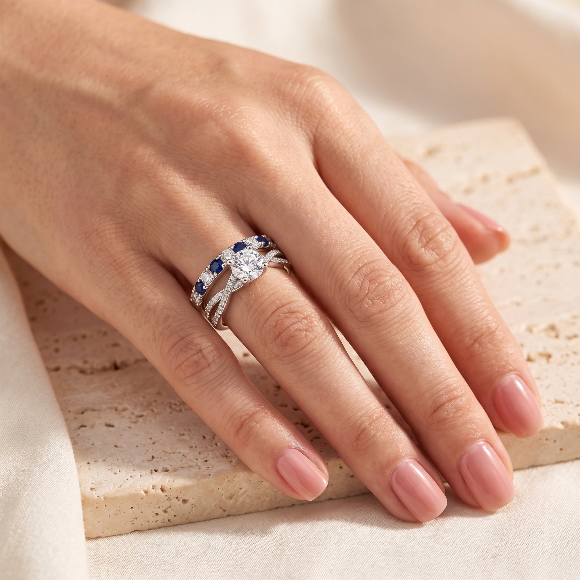 Fiona sterling silver ring set with round cubic zirconia and blue stones shown on a finger.