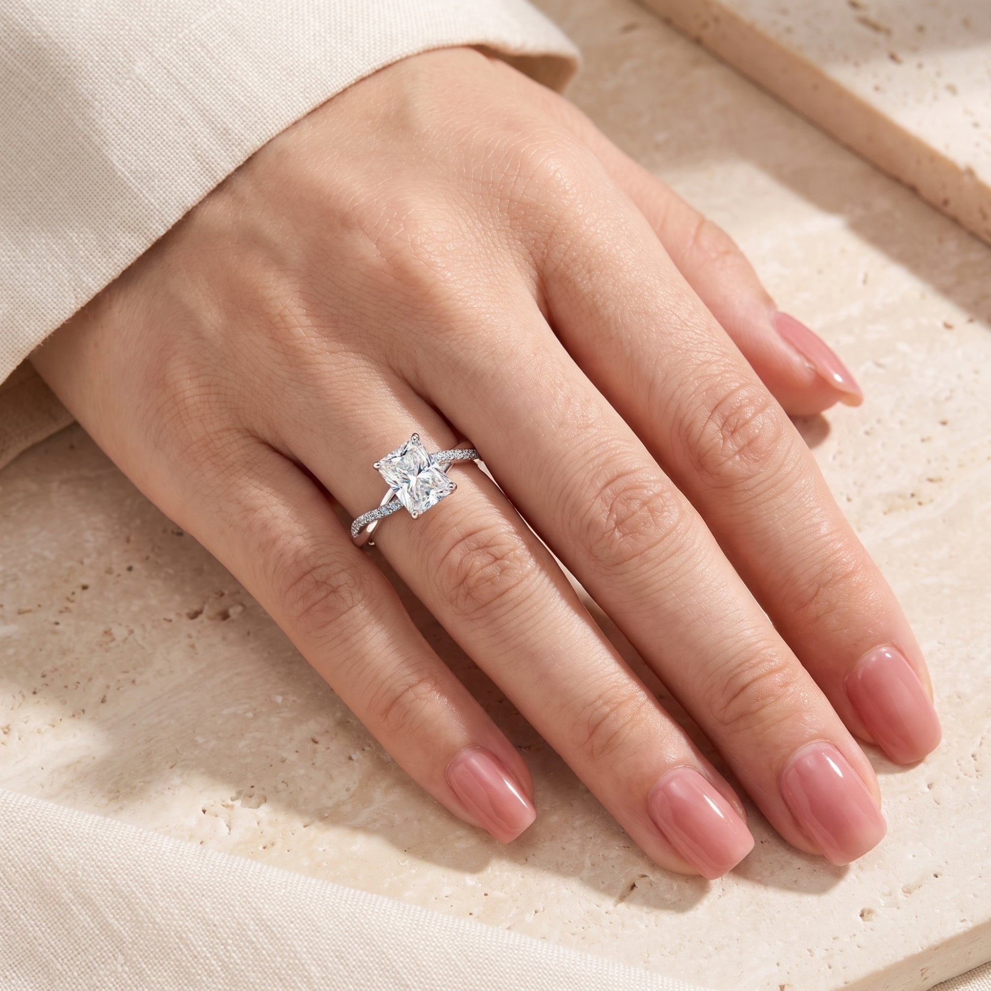 Radiant cut simulated diamond ring in sterling silver worn on a finger.