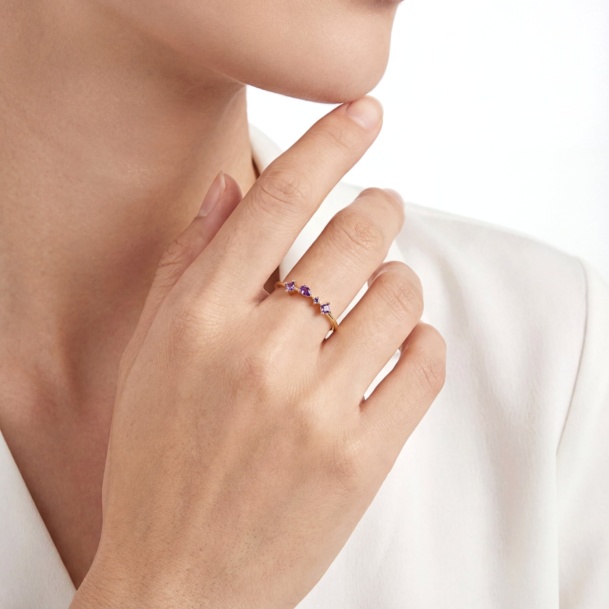 The Elisia gold vermeil ring with princess and pear cut simulated amethyst worn by a model in a white shirt.