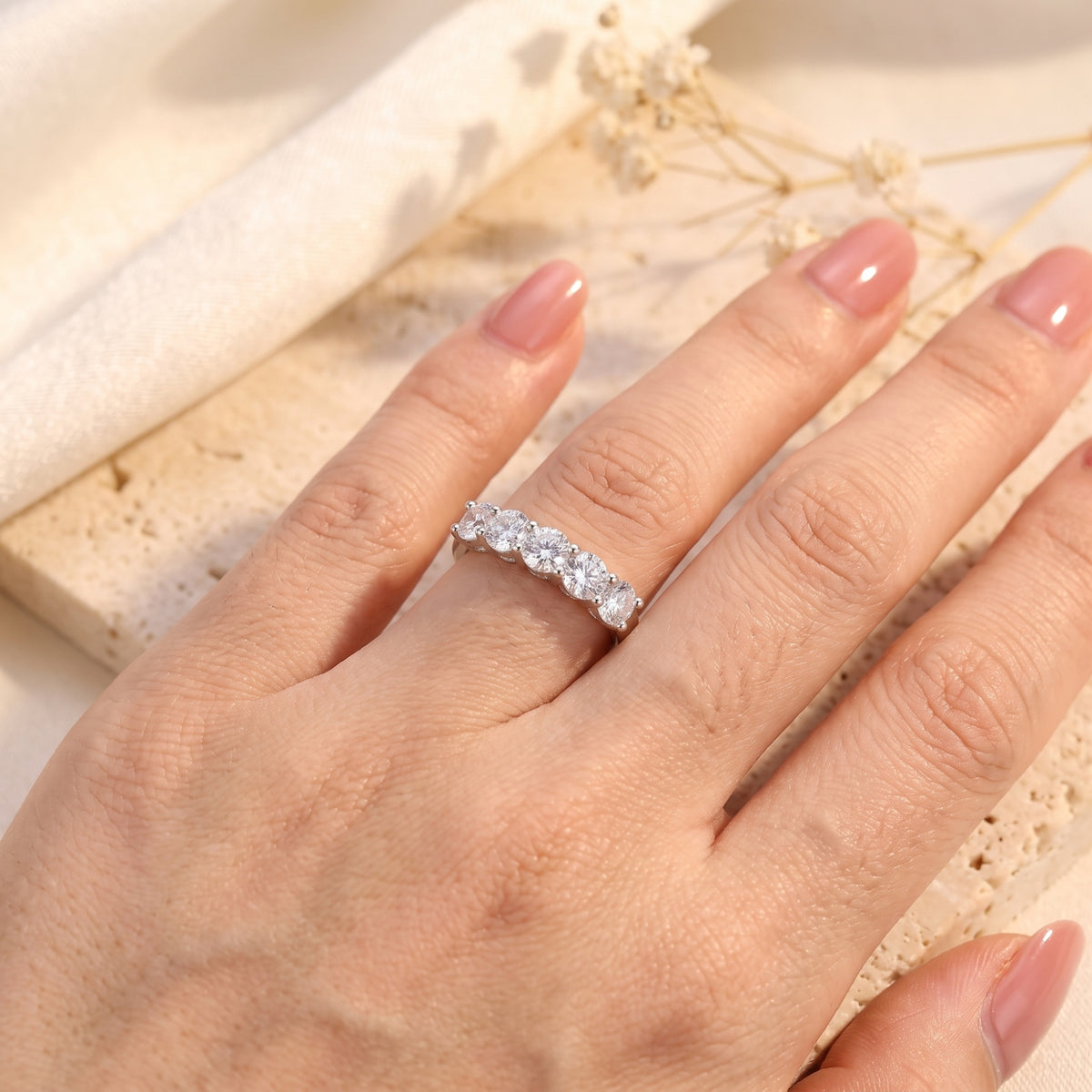 Overhead view of a hand wearing the silver five-stone band ring on the ring finger.