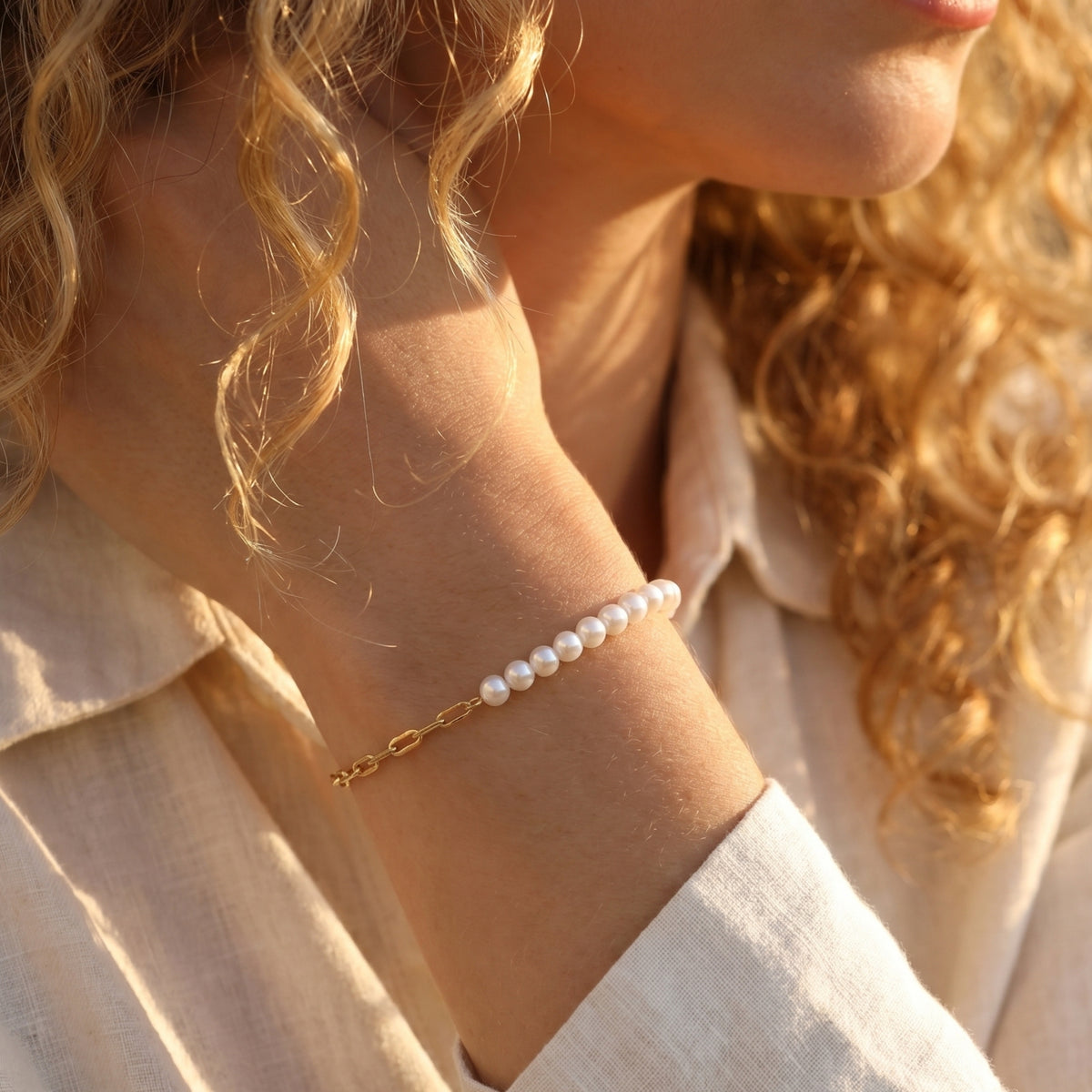 Side view of the solid gold O-chain and pearl bracelet worn on a model's wrist.