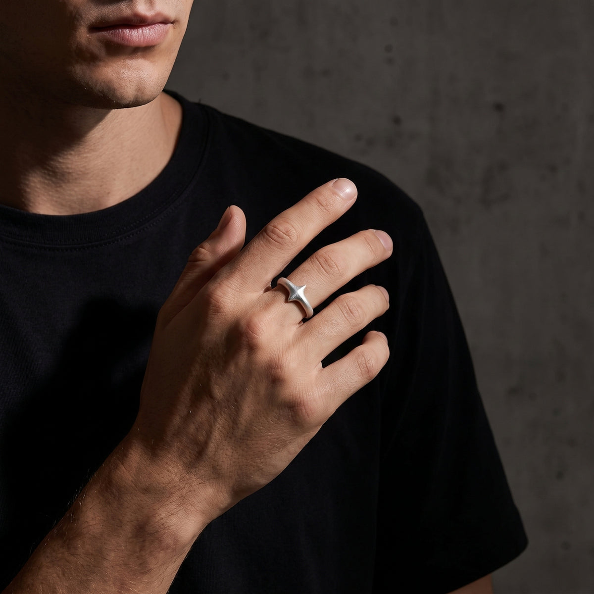 Man wearing the matte silver starburst open band ring across his chest over a black T-shirt.