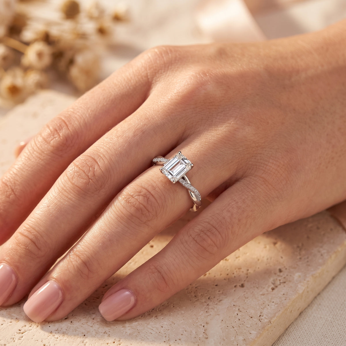 Angled view of a sterling silver emerald cut CZ ring with a twisted band on a model's hand.