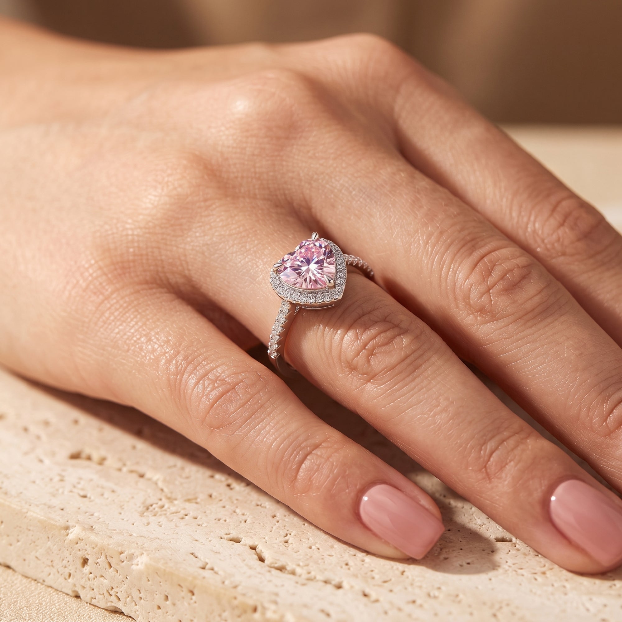 Close-up side view of the Amourette heart-shaped simulated pink tourmaline ring in S925 sterling silver worn on a hand.