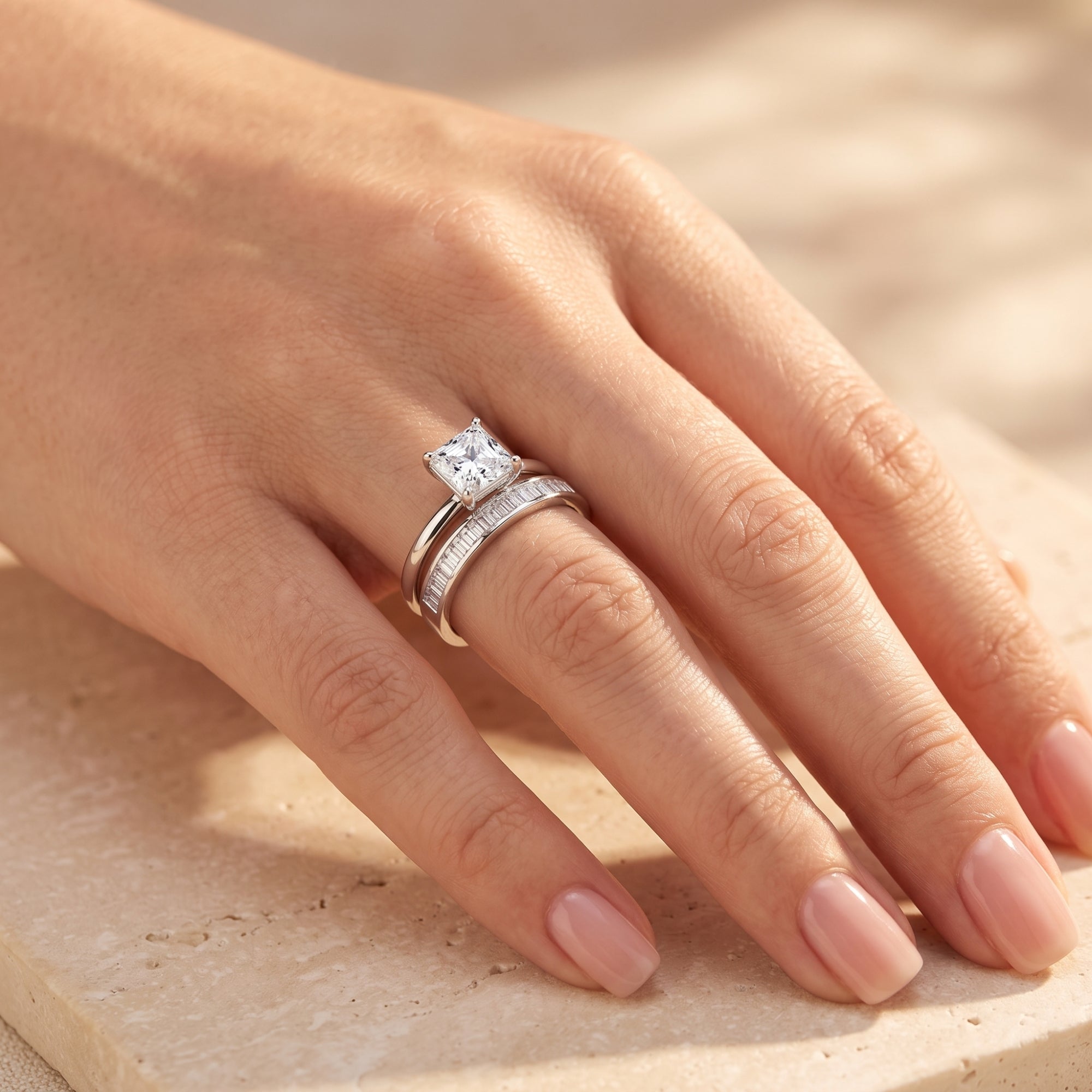 Angled view of the silver Liorienne ring set with a square-cut stone and baguette band worn on a hand.