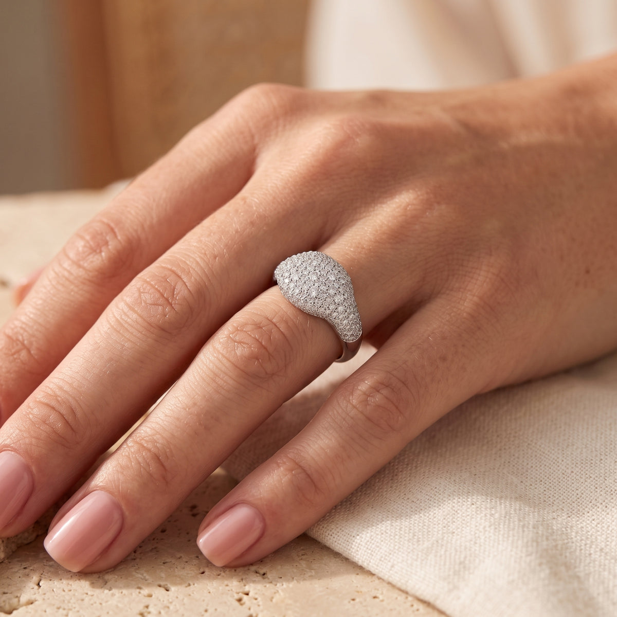 Angled view of a solid gold pave dome ring in white gold worn on the hand, highlighting the raised rounded crown.