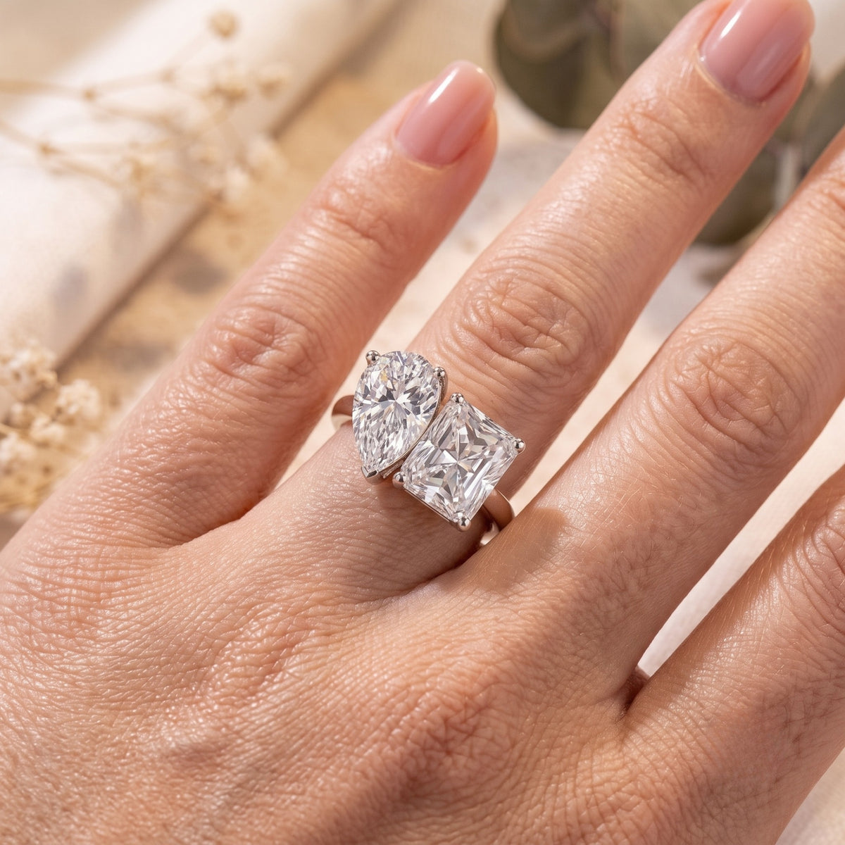 Silver Corentine ring with pear and radiant simulated diamonds shown on a model's finger.