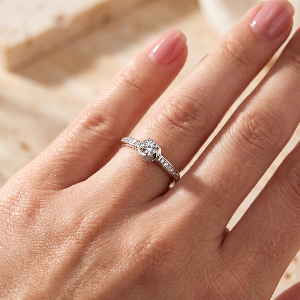 Macro view of the silver Melisande ring's bypass swirl setting and round-cut simulated diamond on a finger.